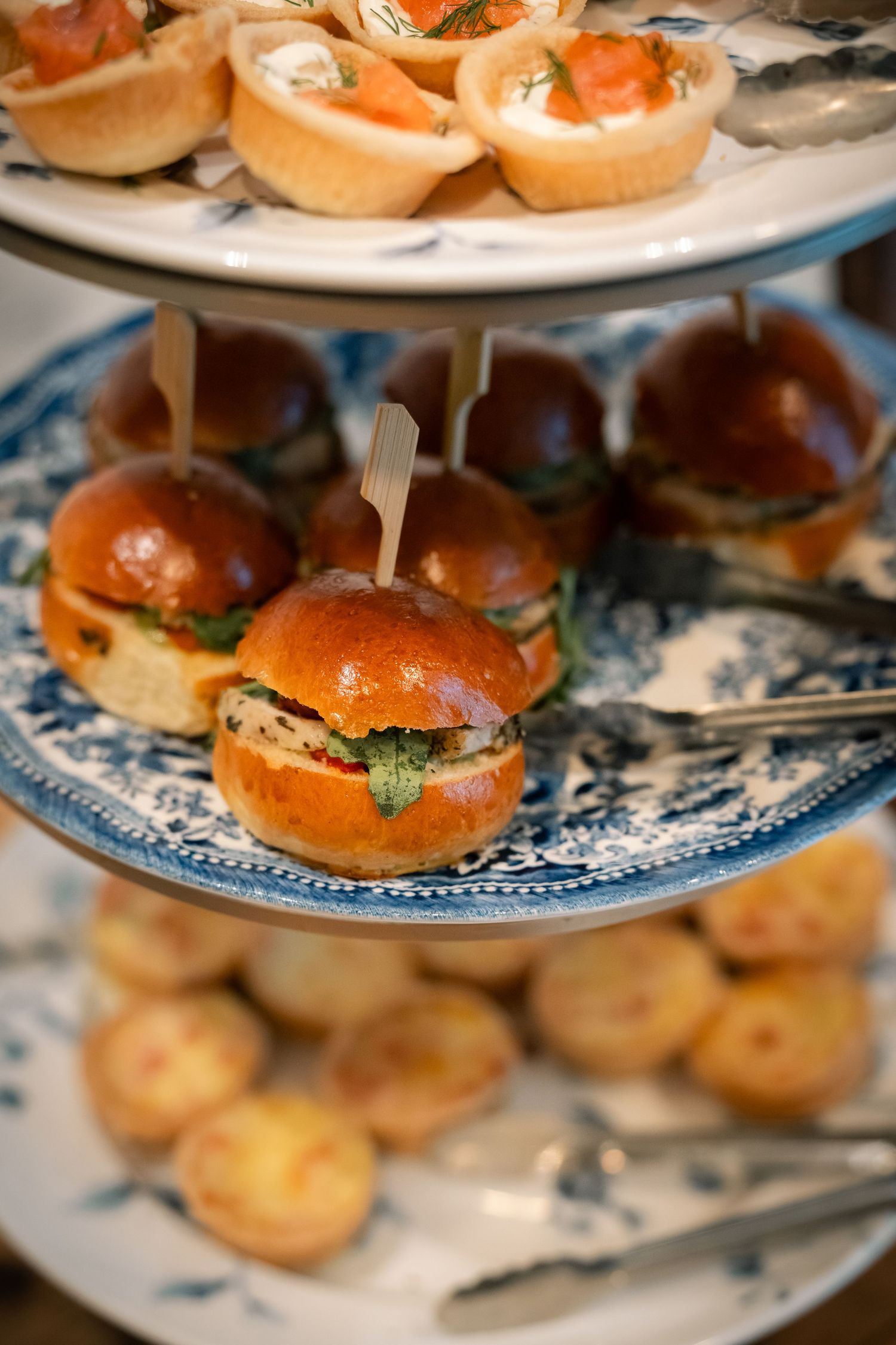 Close-up view of gourmet sliders on blue and white patterned serving plates arranged in a tiered display.