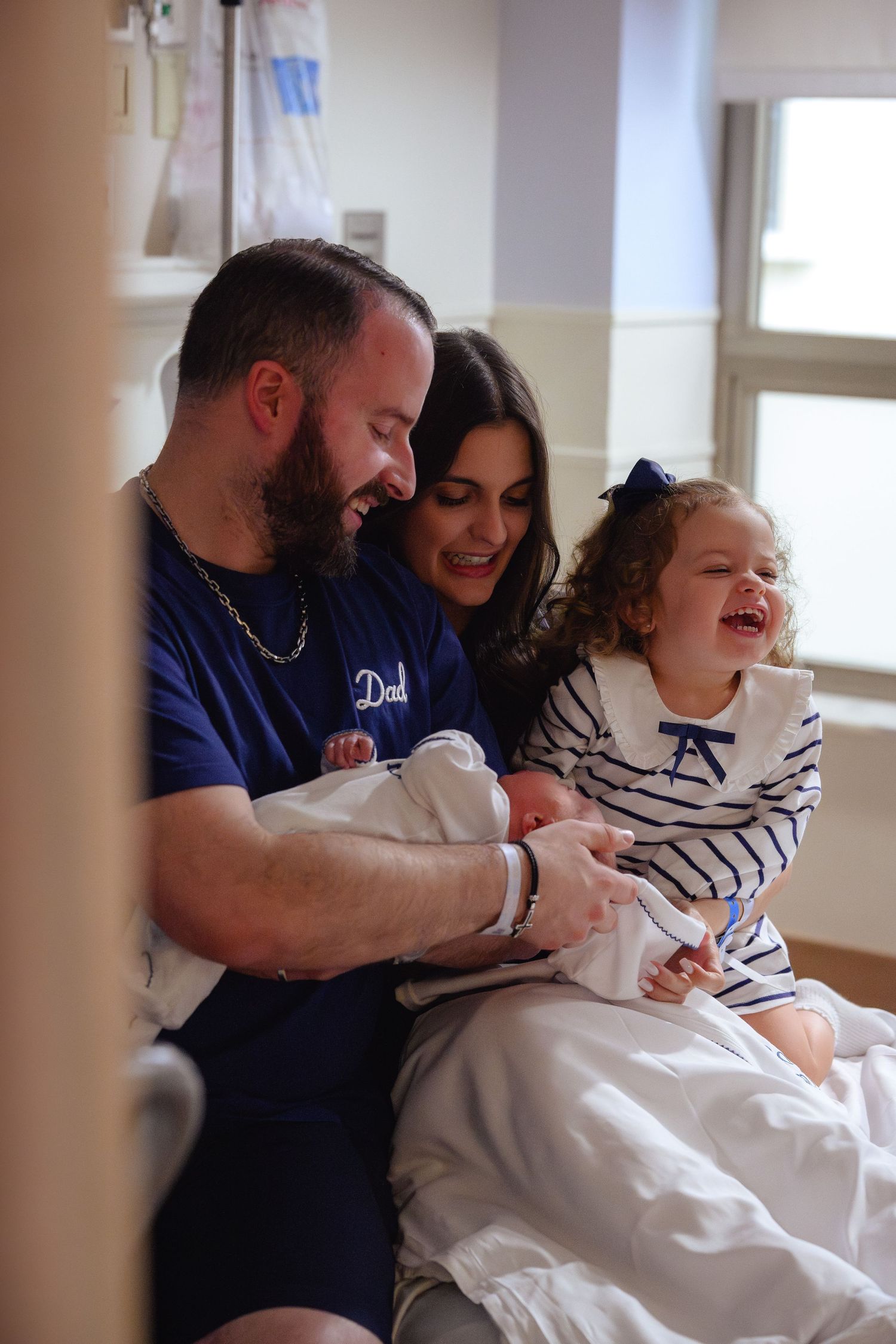 A family shares joyful laughter while sitting together in a bright room with natural lighting.