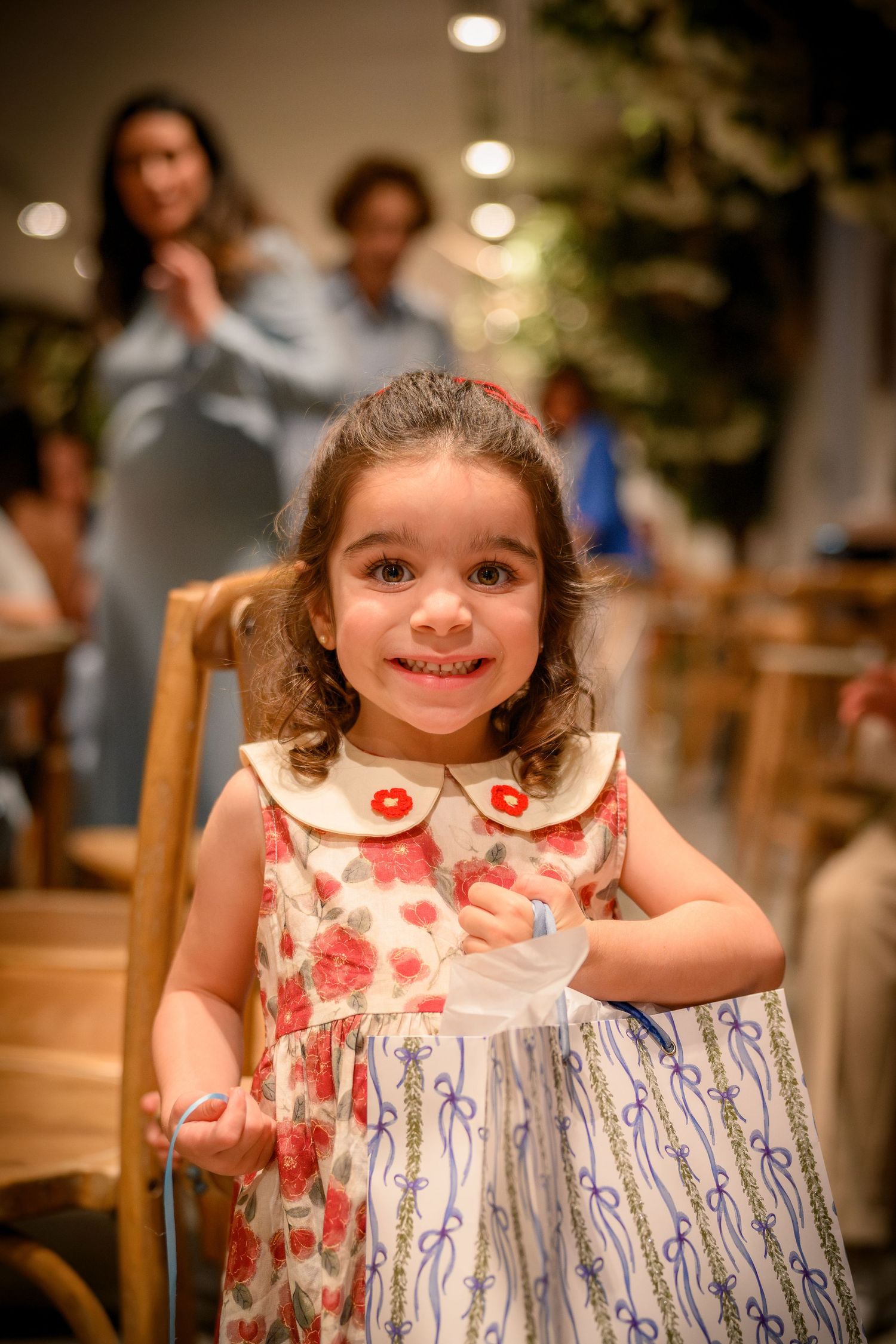 A child in a white floral dress smiles brightly in a series of three candid indoor photos.