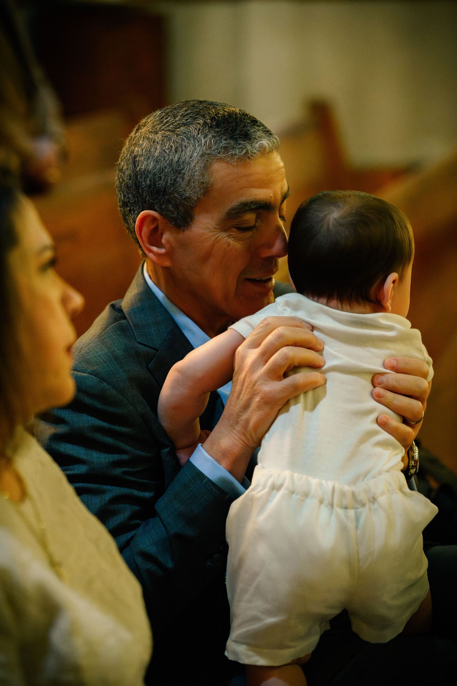 A candid moment between a grandfather and his grandson during the ceremony of a Catholic baptism at St. Raymond, Coral Gables, Miami, FL