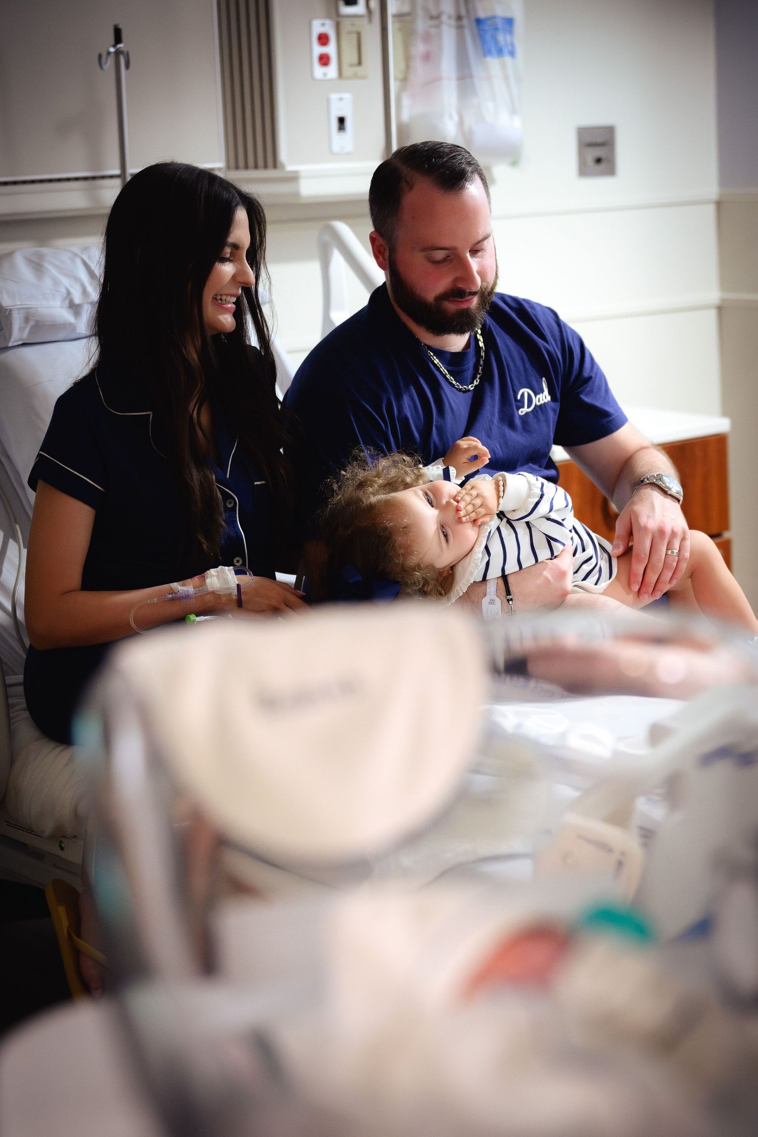 Medical staff attend to a patient in a hospital room while monitoring vital signs and providing care.
