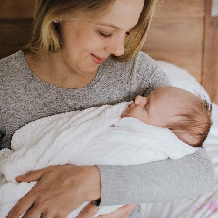 Mother holding newborn baby, intimate natural light newborn photography moment