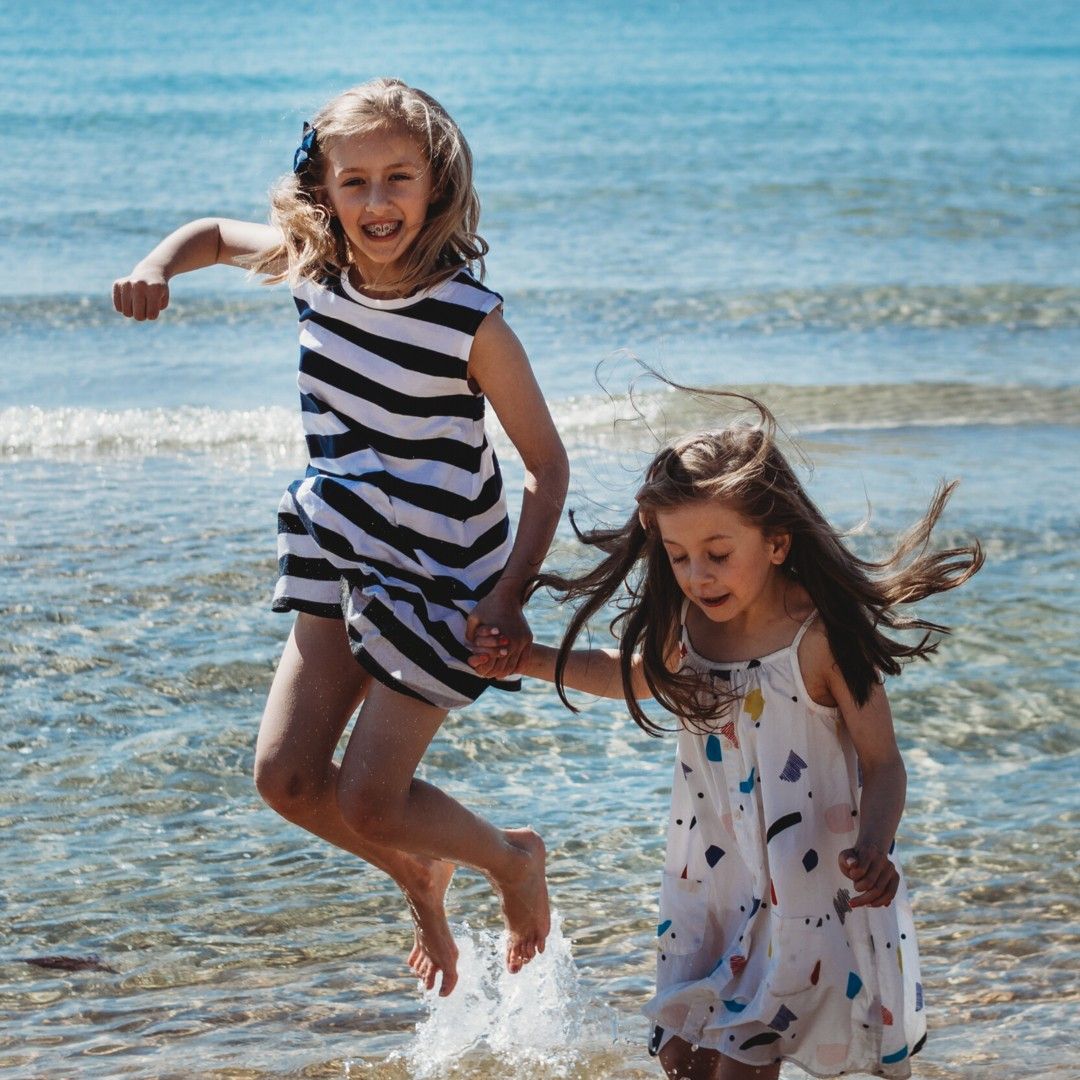 Children jumping and playing in the ocean, fun candid beach photography