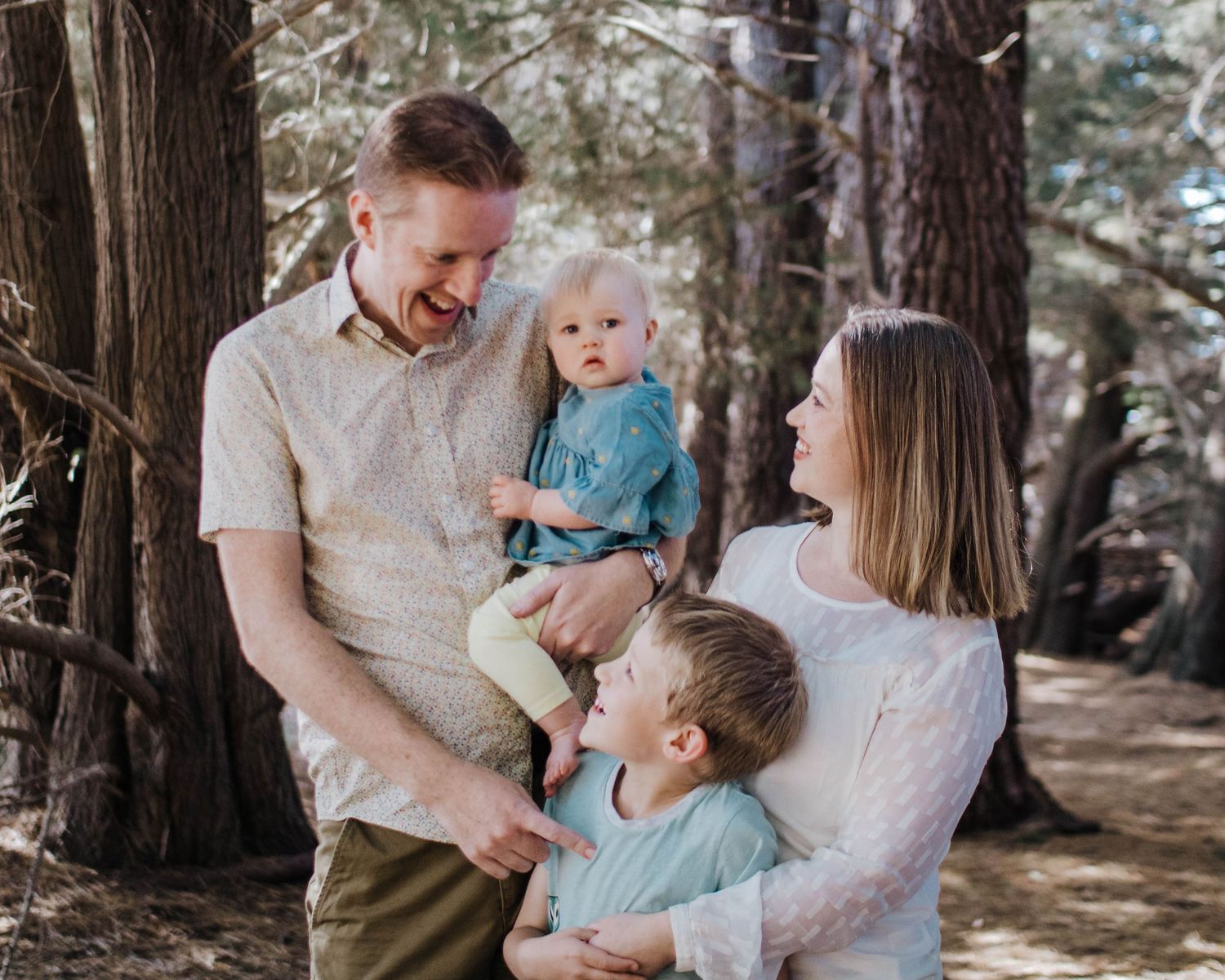 Family standing together in wooded area, relaxed and natural outdoor family photography