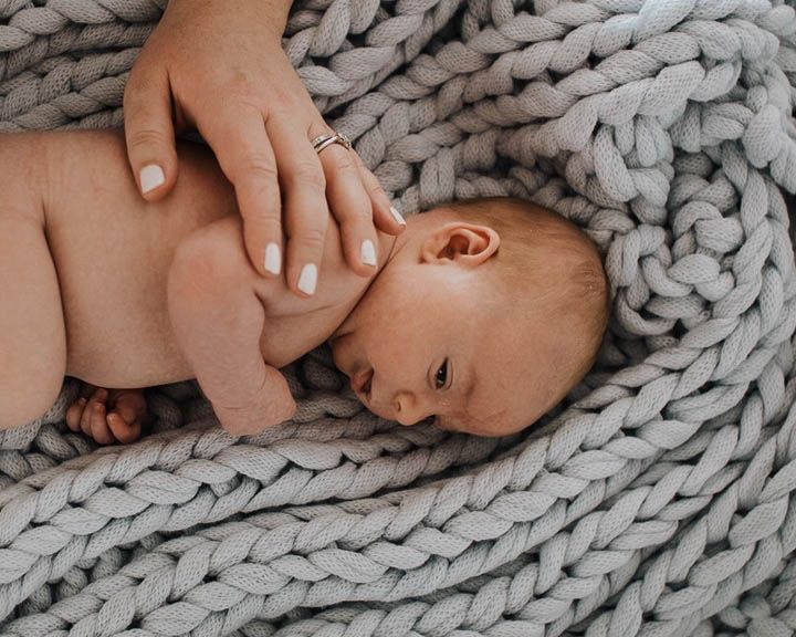 Newborn baby wrapped in soft blanket, natural newborn photography with gentle tones