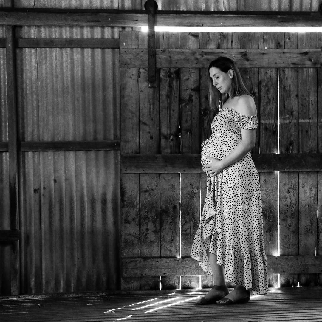 Black and white maternity portrait, expecting mother standing in soft natural light