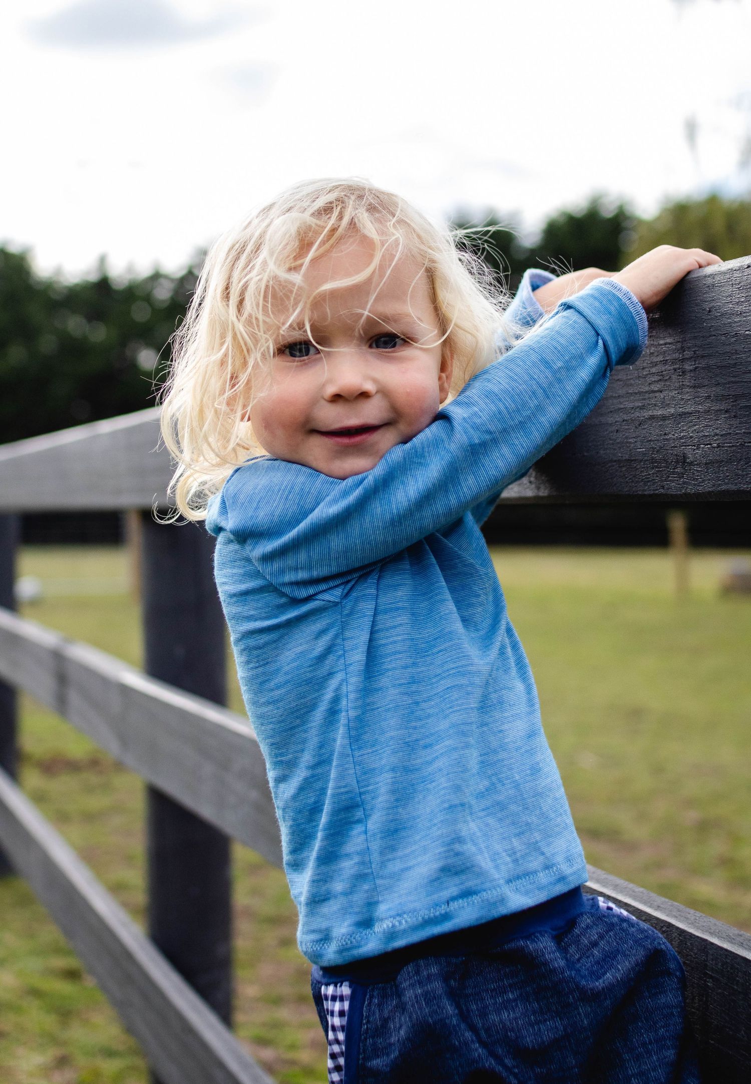 Young child leaning on wooden fence, natural light outdoor portrait on the Mornington Peninsula
