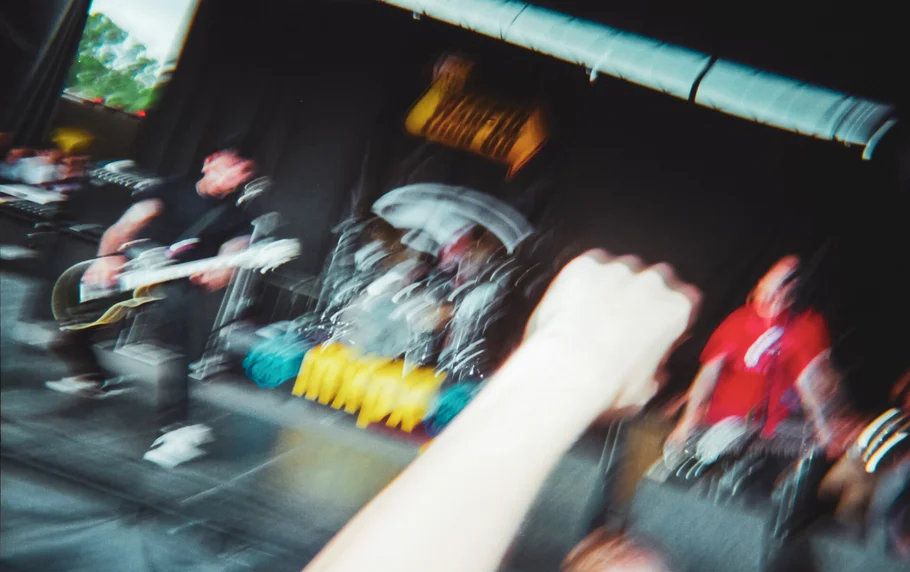 Motion-blurred photo of band performing energetically on outdoor festival stage at Warped Tour.