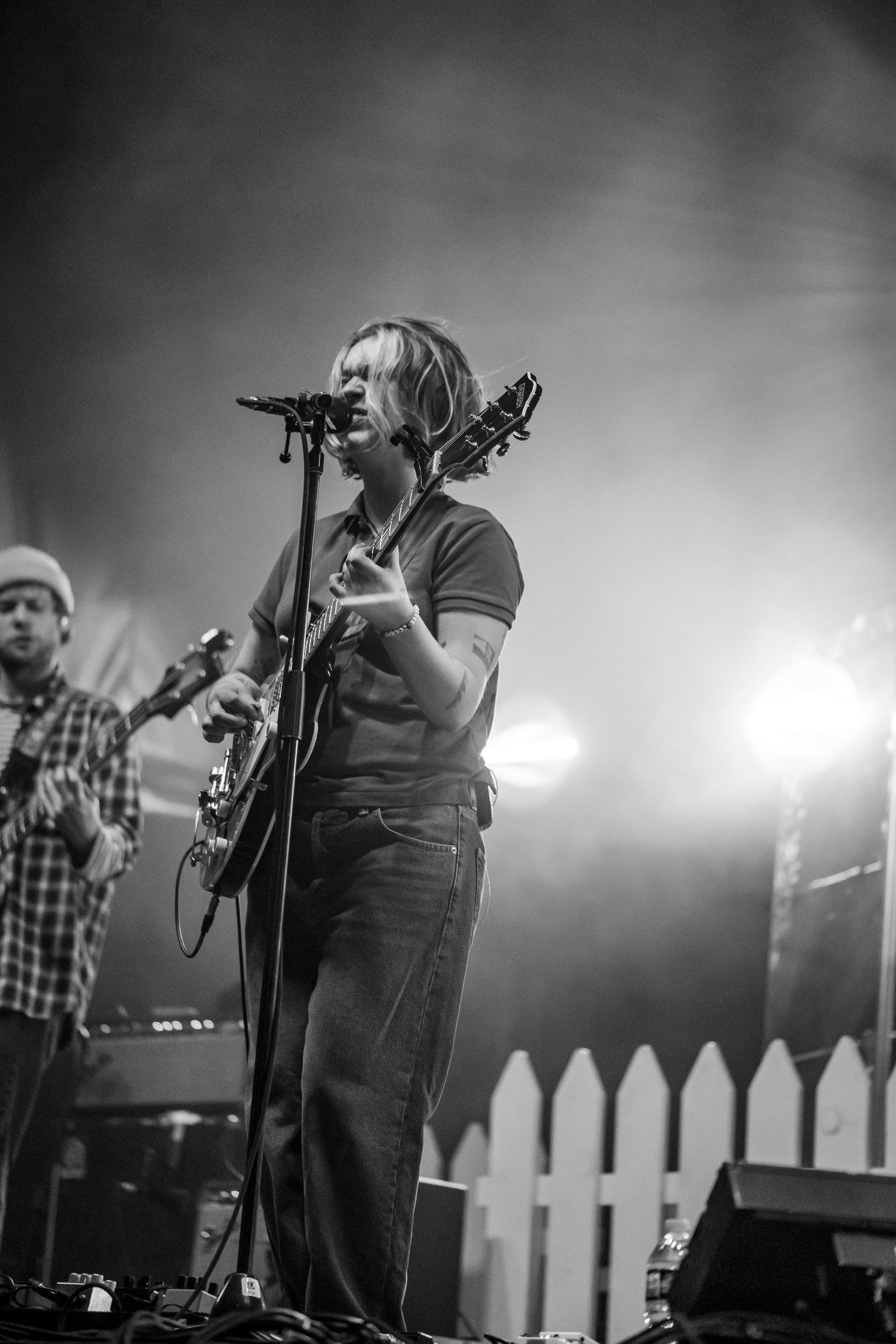 Black and white photo of a singer-guitarist performing passionately on stage with bright backlighting.