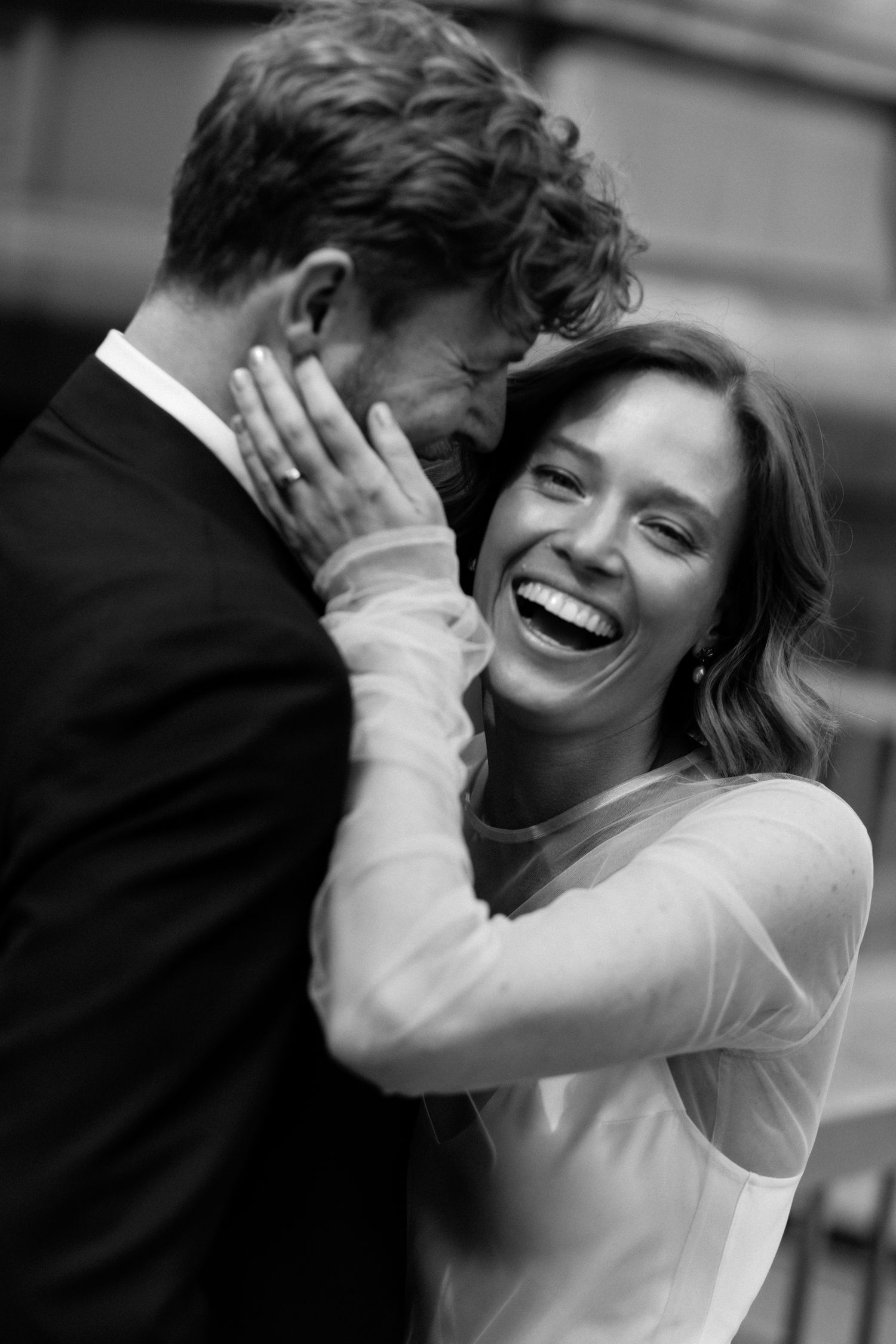 Black and white close-up of smiling bride and groom embracing tenderly on their wedding day.
