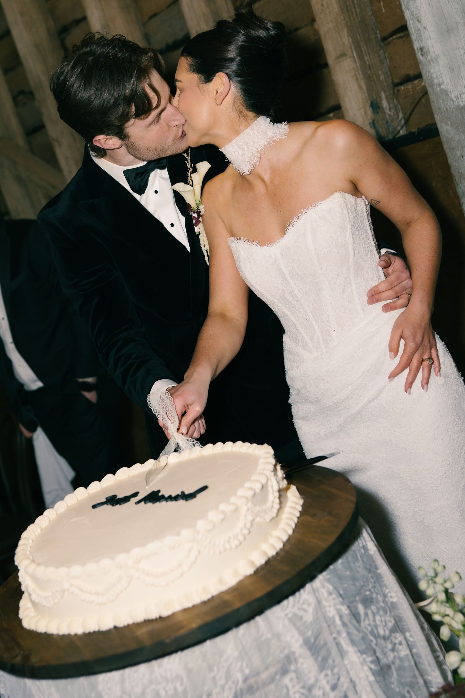 Bride and groom sharing a kiss while cutting their white wedding cake inscribed with Just Married.