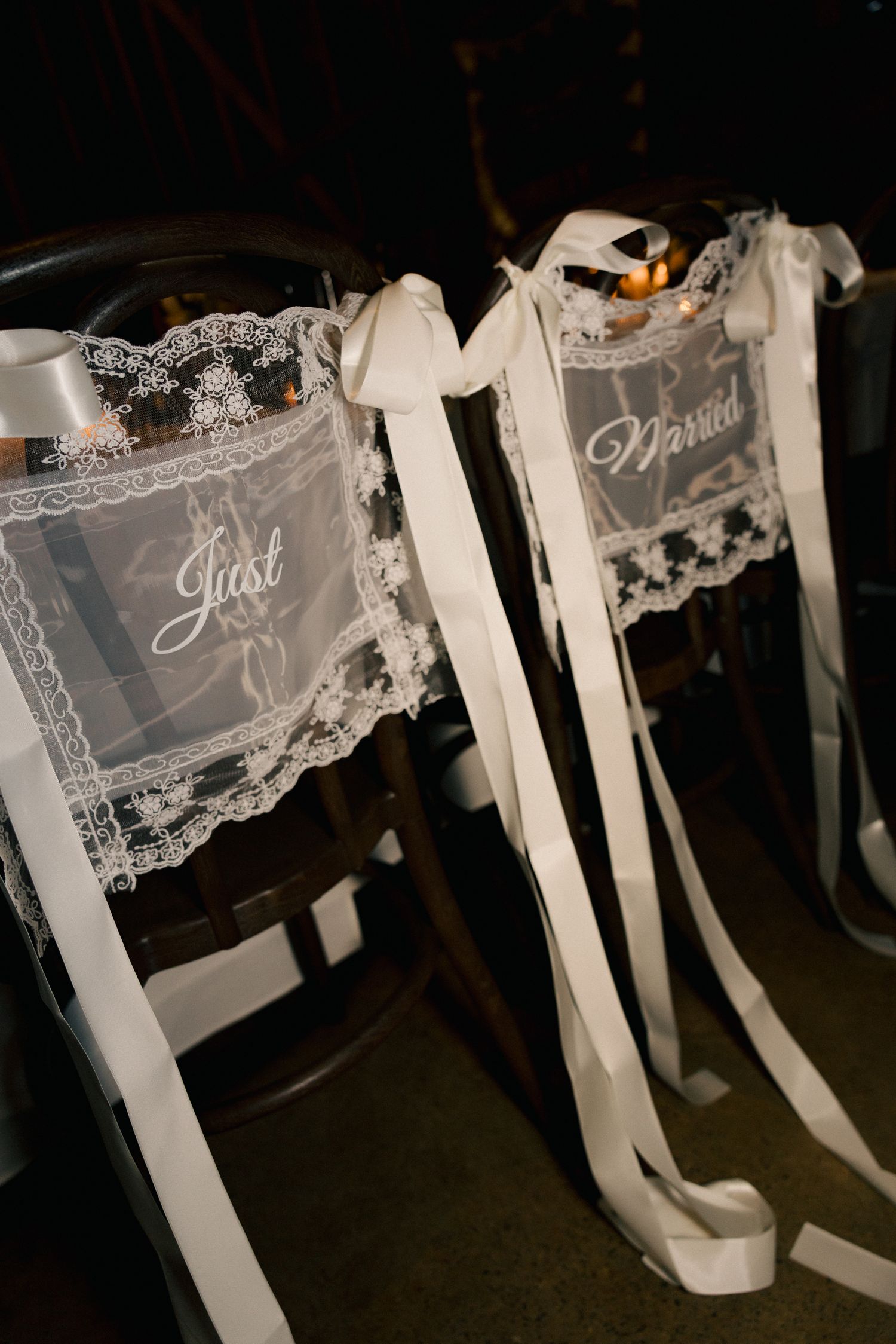Elegant lace Just Married chair signs with white ribbon bows at a wedding reception.
