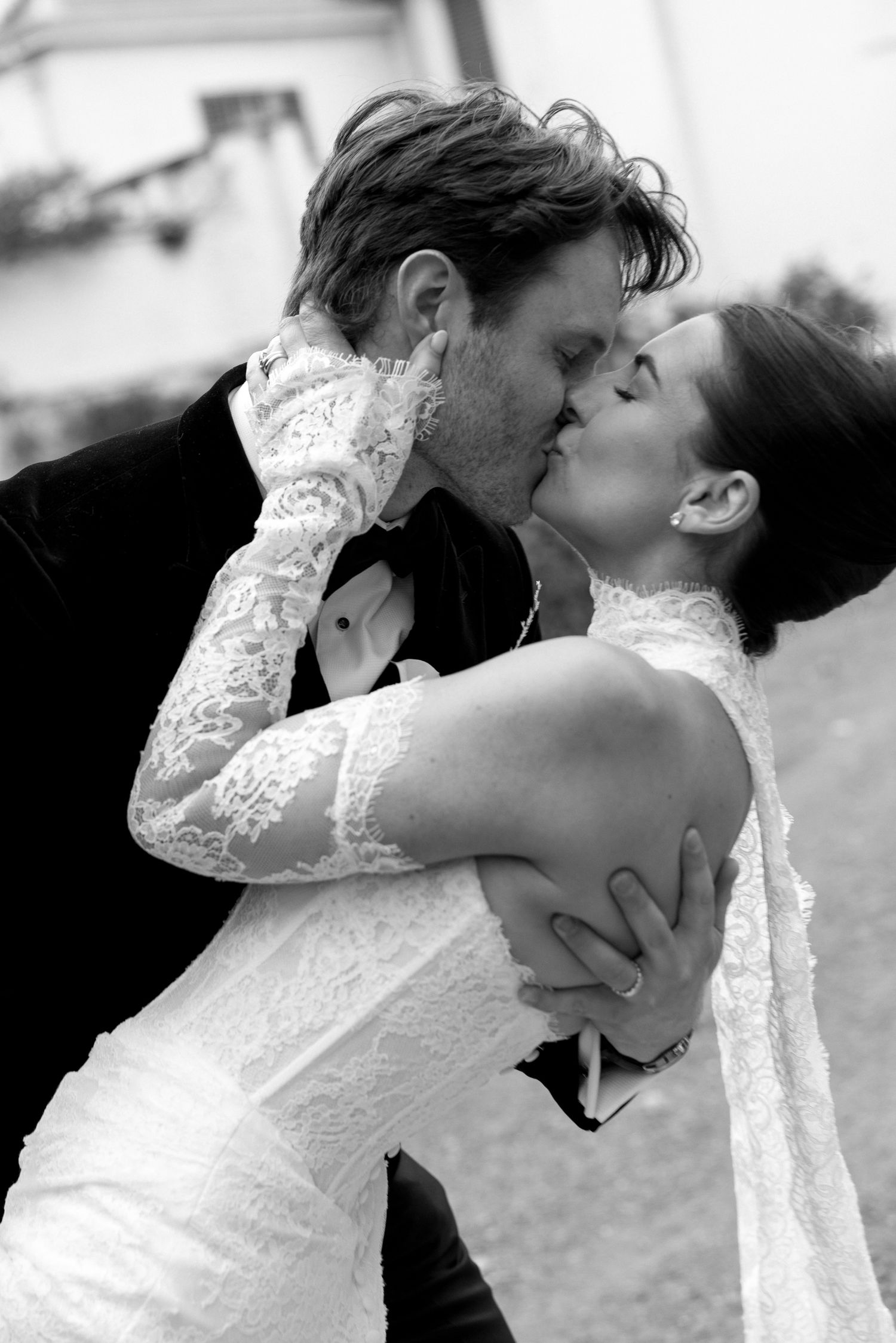 Black and white photo of a bride and groom sharing a romantic kiss on their wedding day.