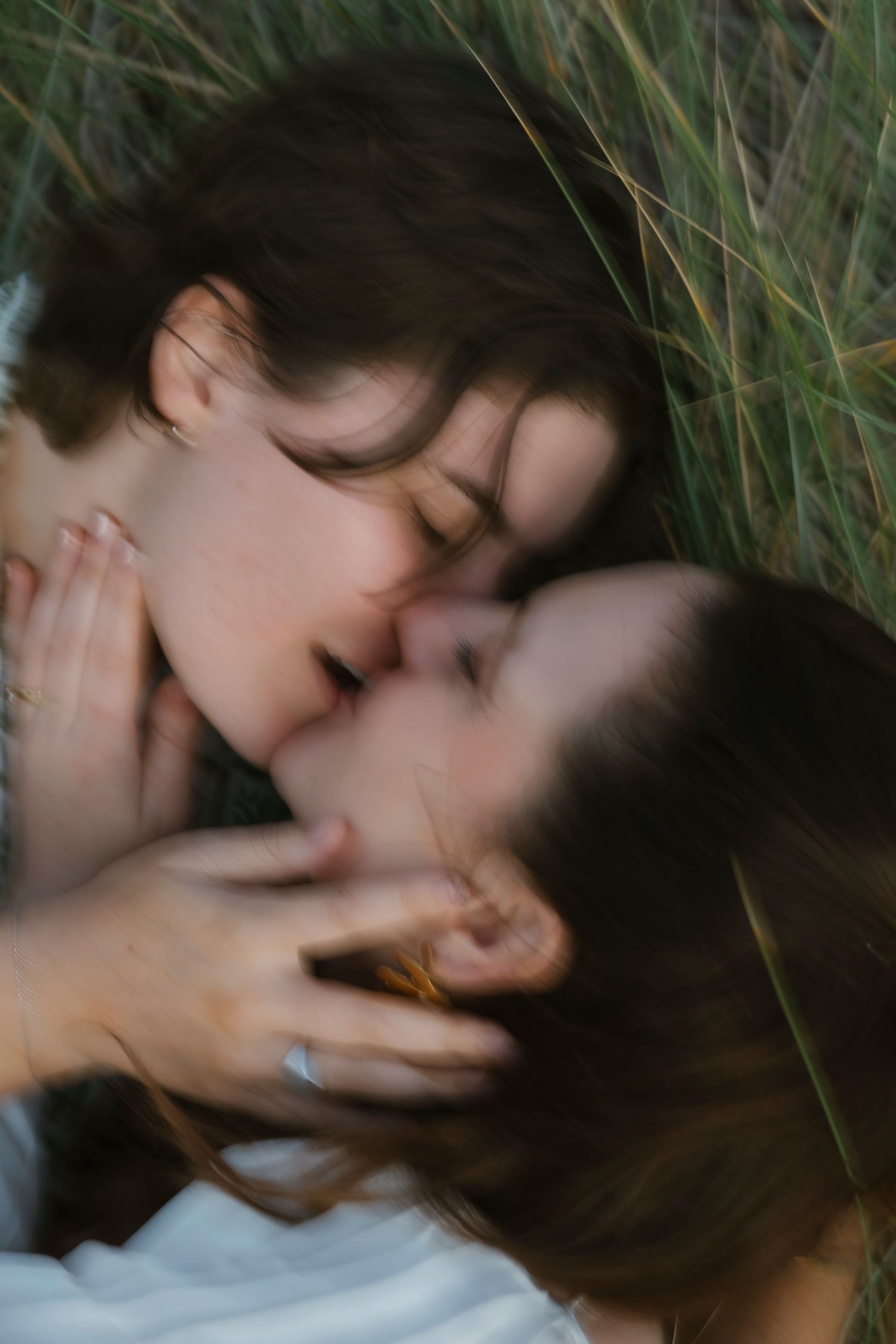 Artistic blurred close-up of couple lying in grass sharing an intimate romantic moment on their wedding day.