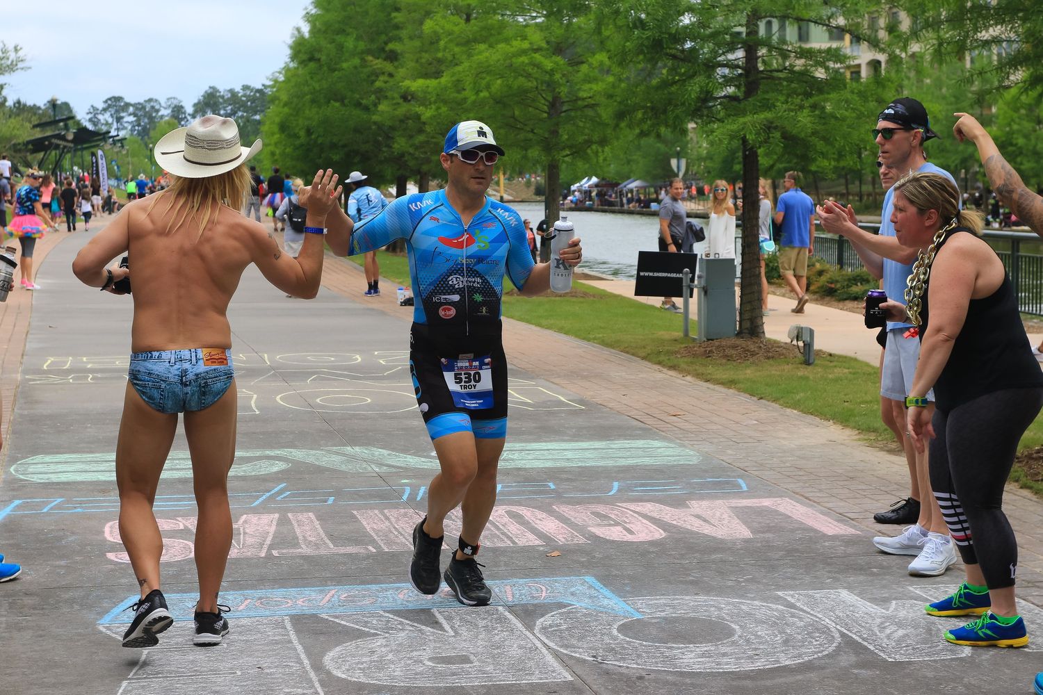 Triathlete receives high-five from spectator on chalk-decorated finish line path during outdoor race event.