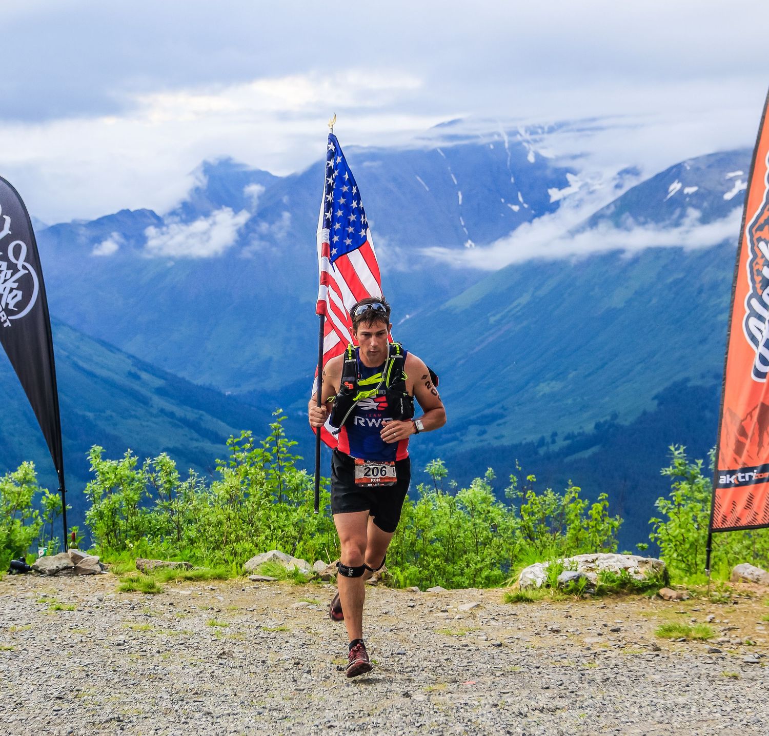 Trail runner carries an American flag near the summit during Alaskaman Extreme Triathlon.