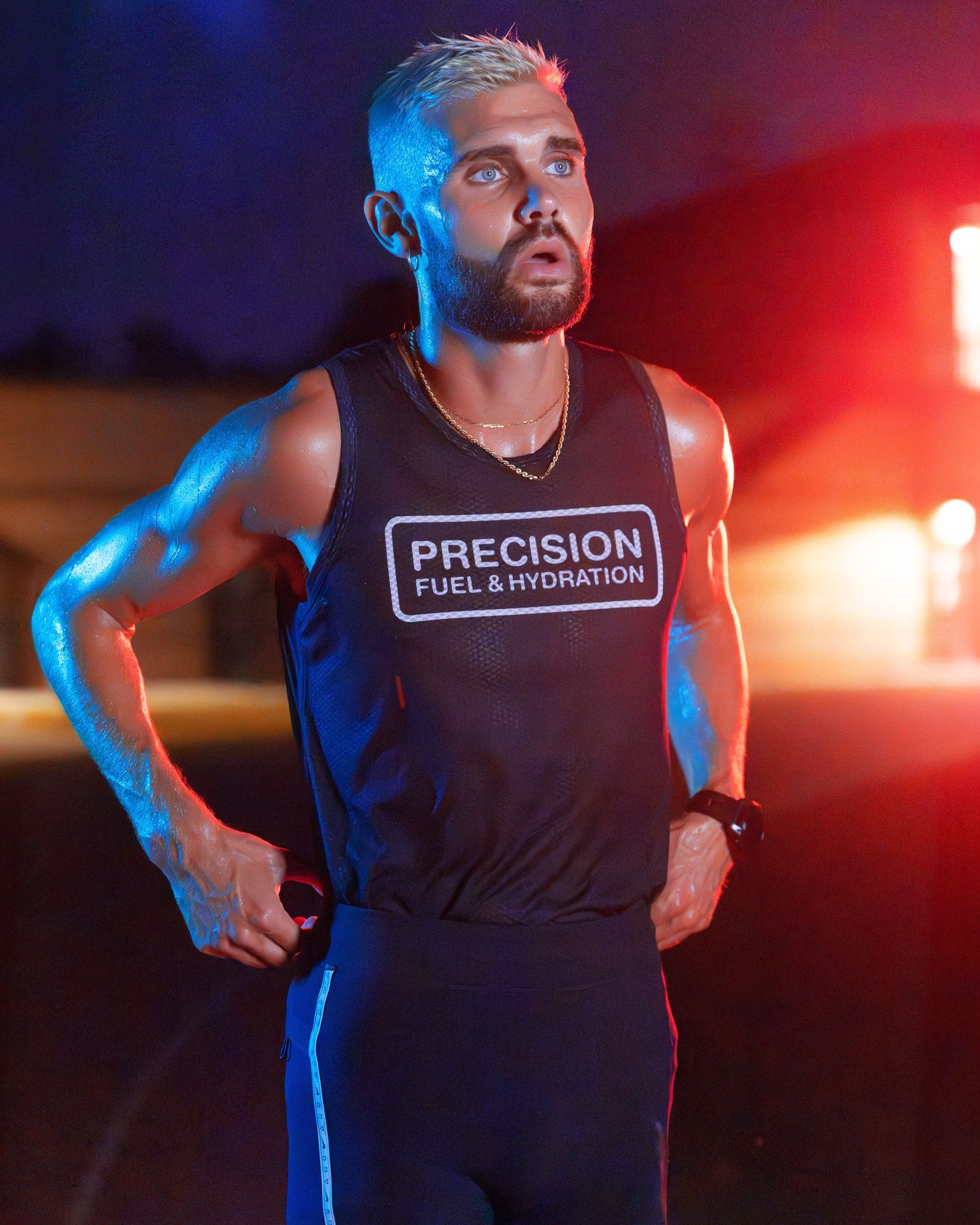 Male runner in Precision Fuel and Hydration vest training at night under blue and red lights.
