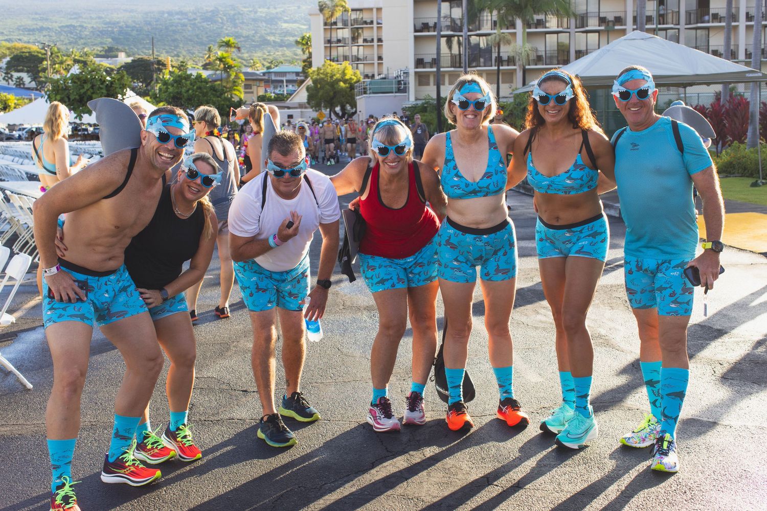 Group of seven friends in matching blue patterned swimwear posing at the Kona Underpants Run.