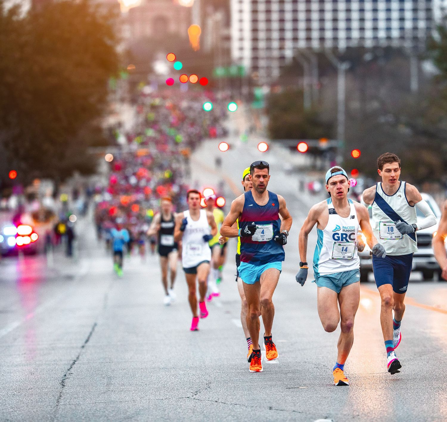 Large group of marathon runners race down Congress Avenue at dawn during the Austin Marathon.