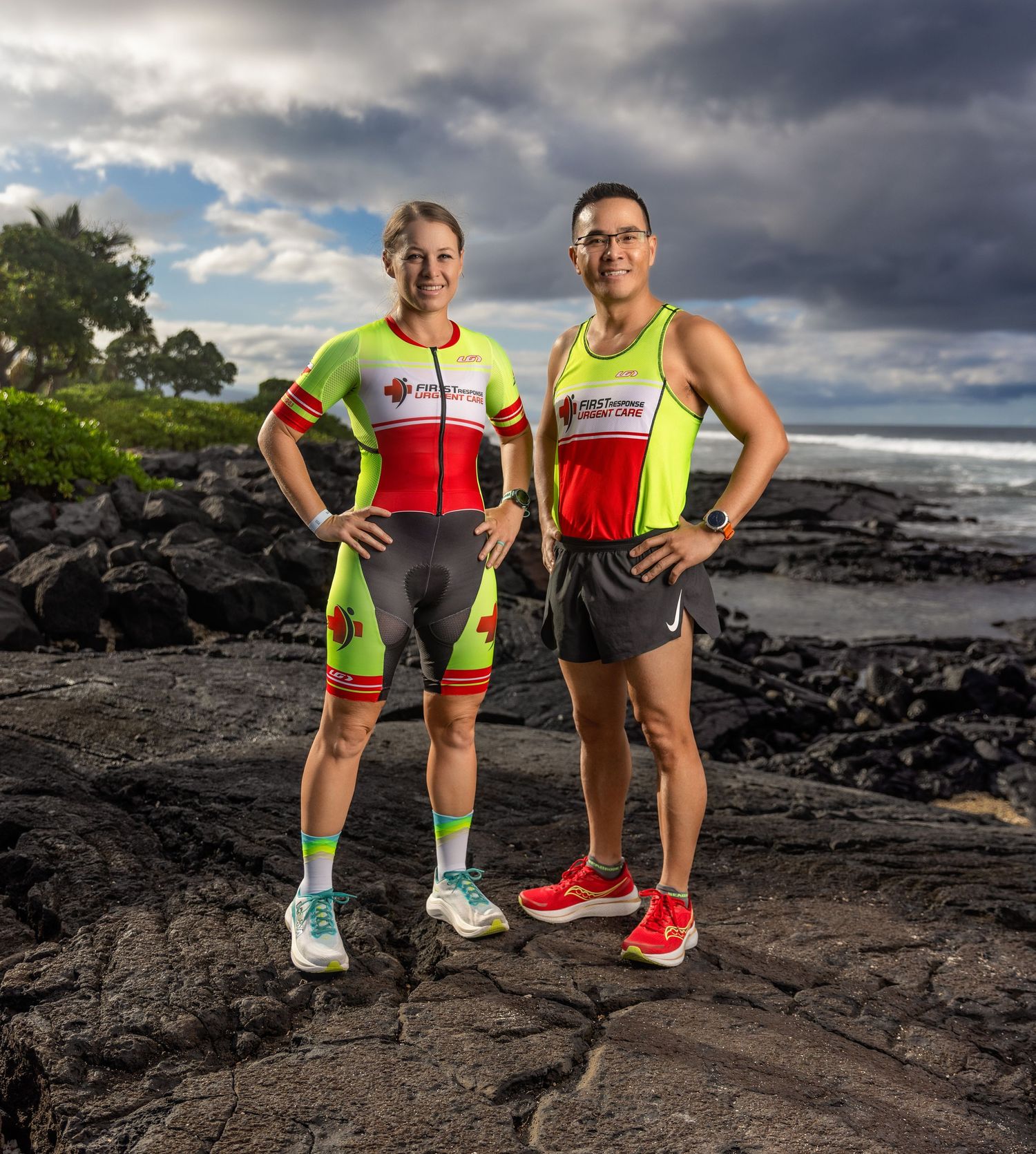 Male and female triathletes in colorful race kits posing on volcanic rocks.