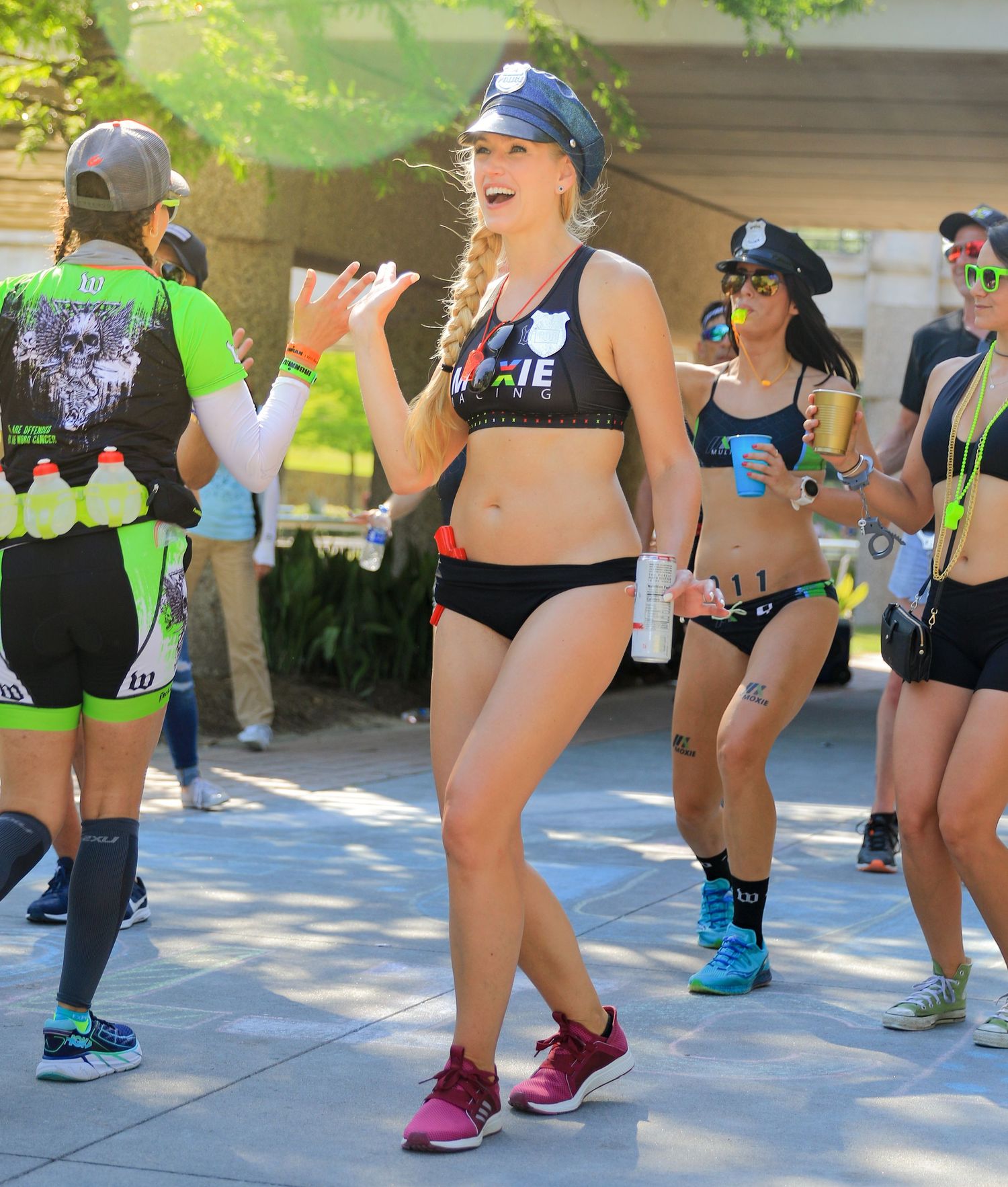Female runner in police costume waves during festive themed triathlon or fun run event.