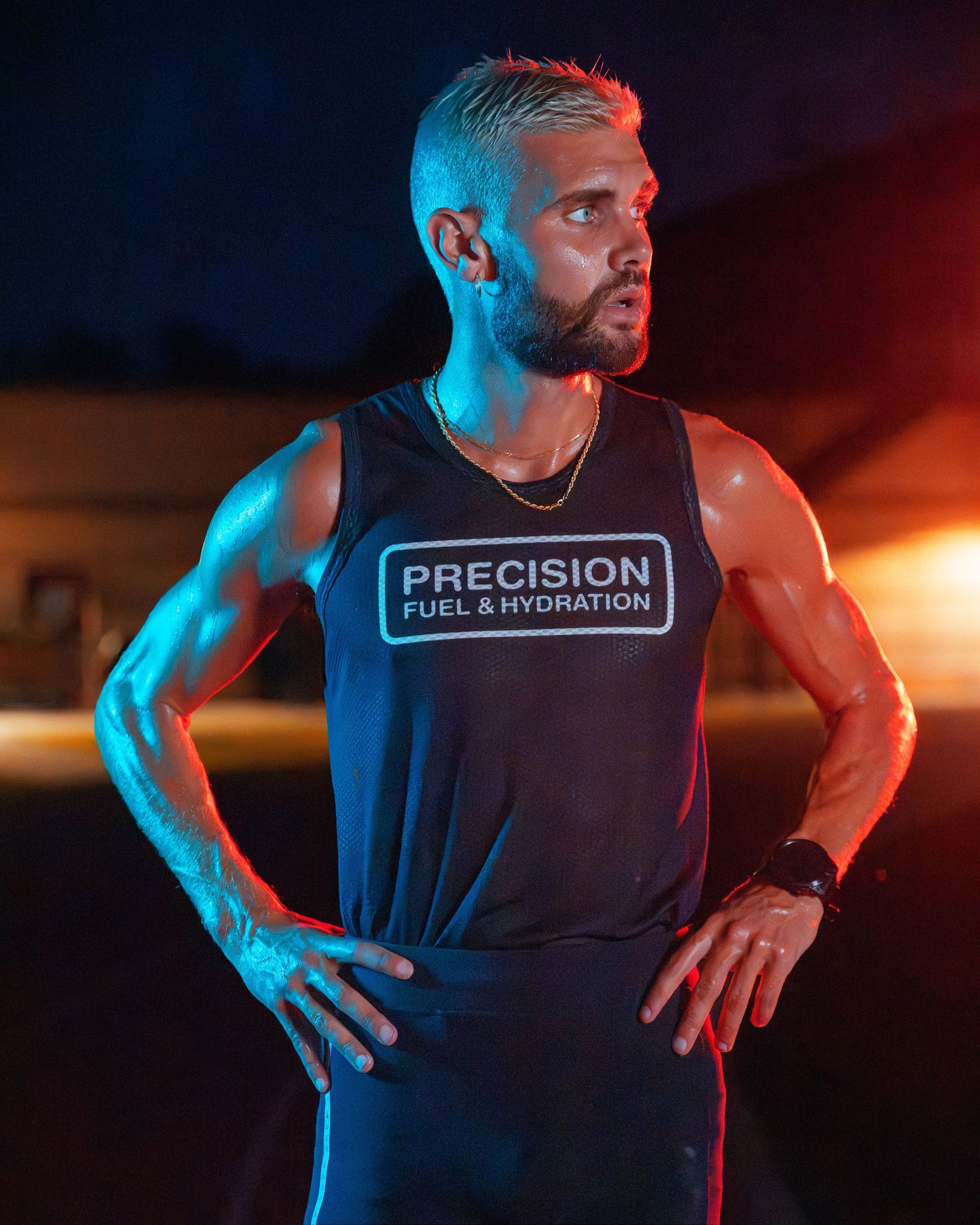 Muscular male athlete in Precision Fuel and Hydration tank top posing under dramatic neon lighting.