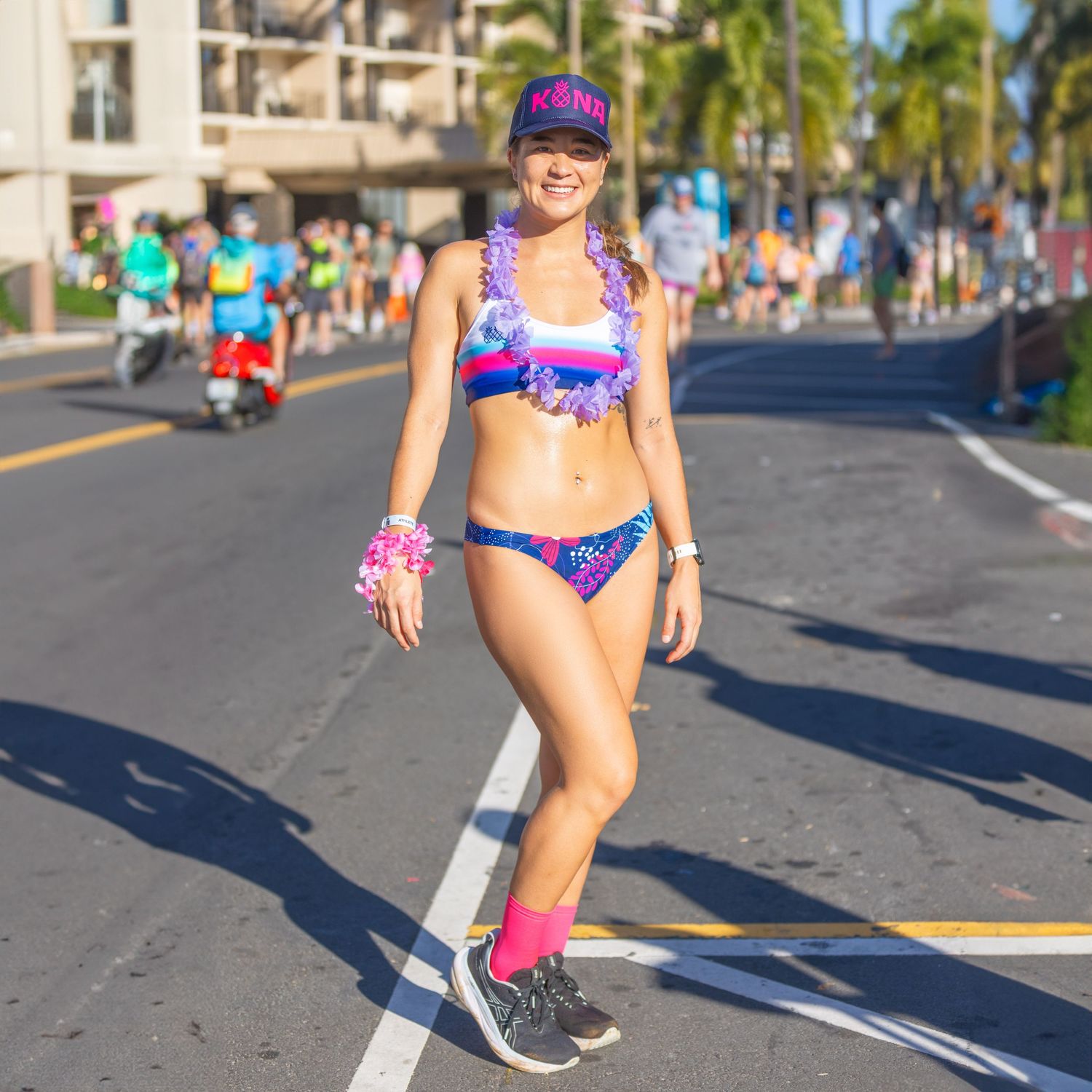 Woman in colorful bikini and pink socks walking on a sunny race course road at the Kona Underpants Run.