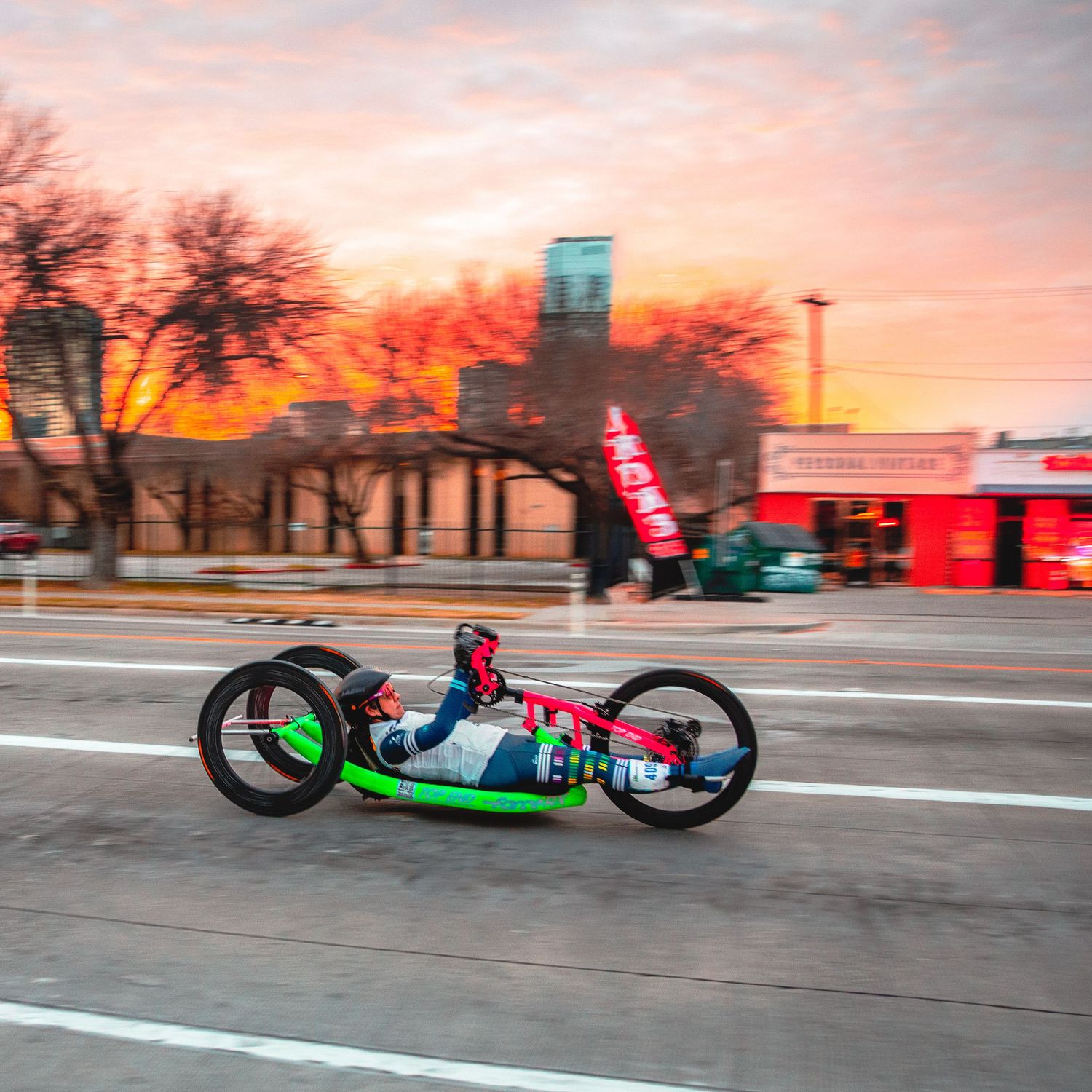 Handcycle athlete races down an urban street at sunrise in the Austin Marathon.
