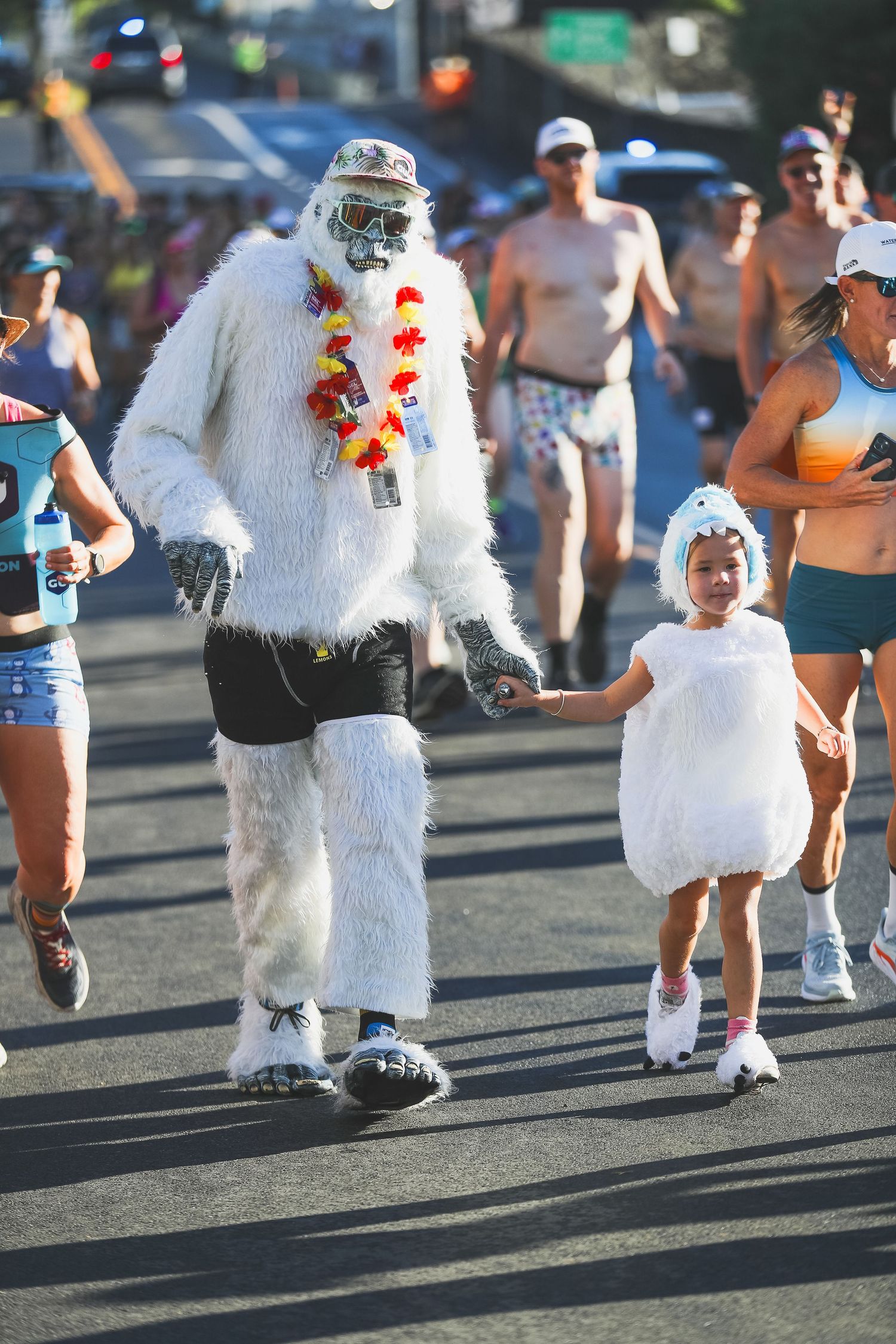 Person in white yeti costume holding hands with child in matching outfit at the Kona Underpants Run.