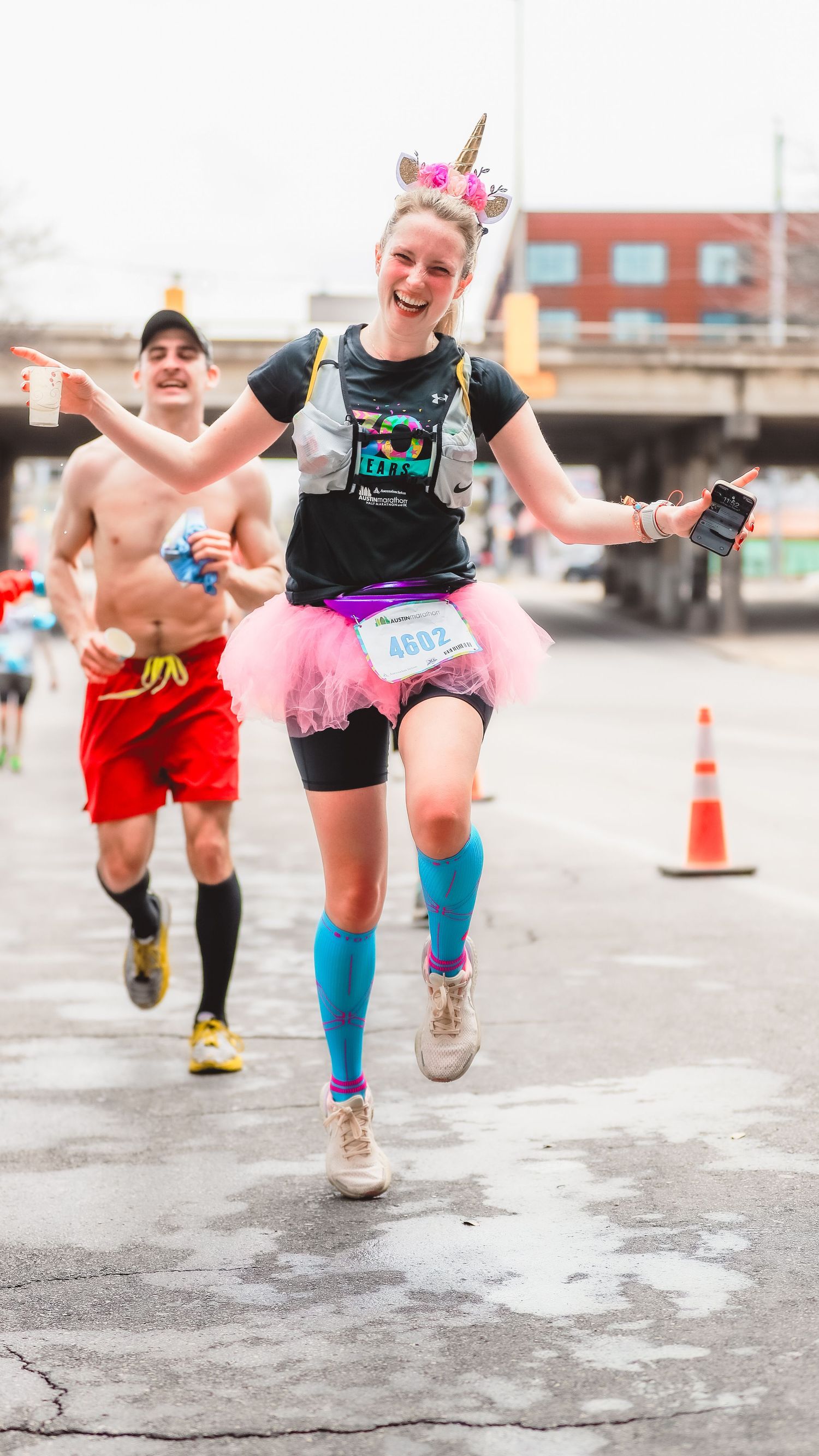Joyful runner in a pink tutu and unicorn headband races at the Austin Marathon.