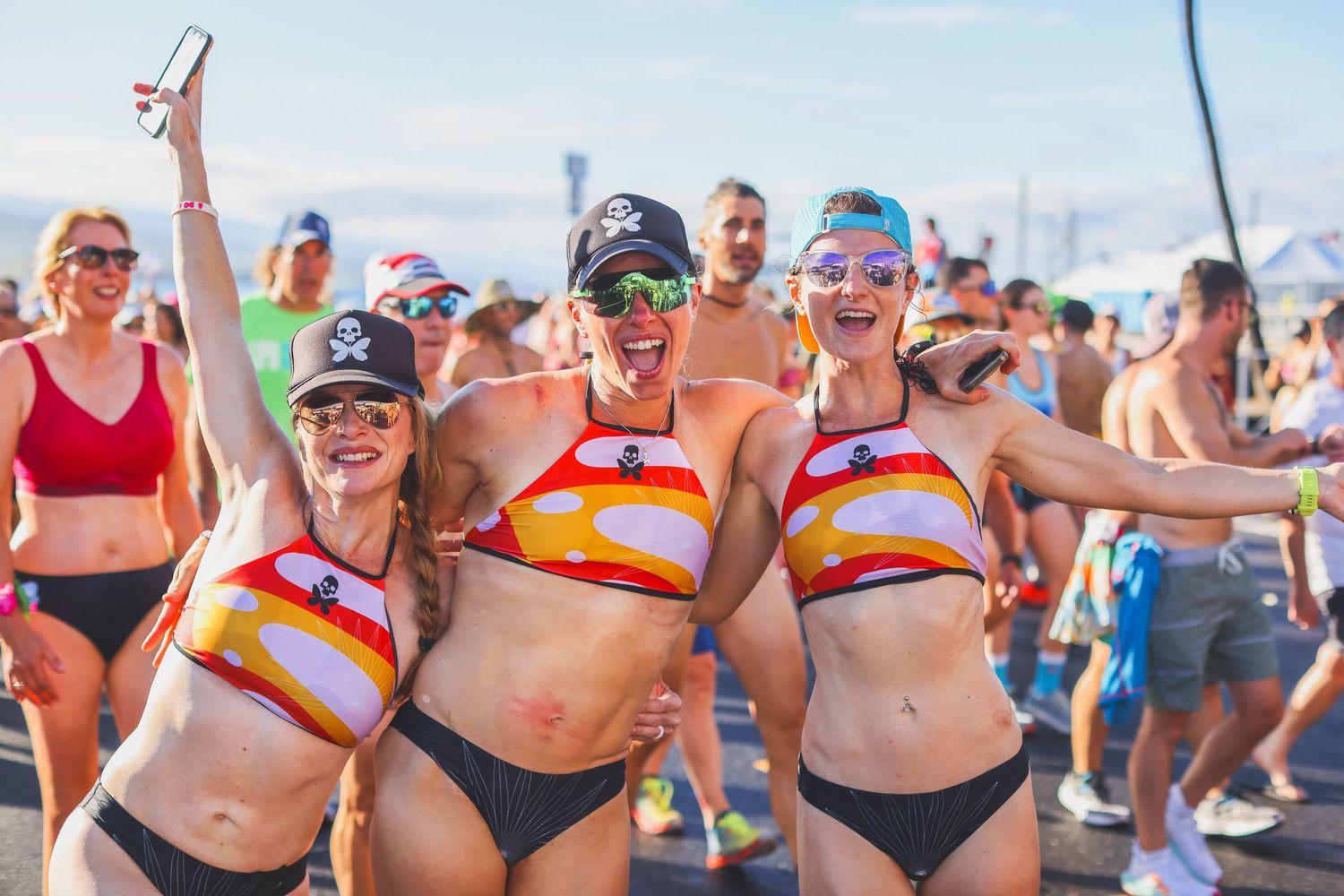 Three excited women in colorful German flag bikinis celebrating together at the Kona Underpants run.