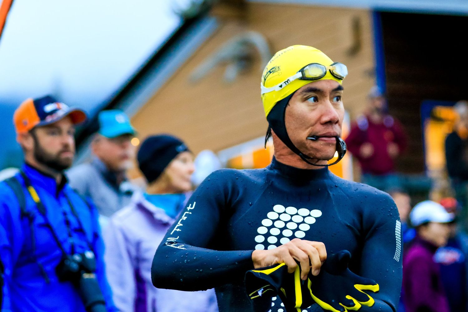 Triathlete in yellow wetsuit and goggles prepares at the starting line of a race.