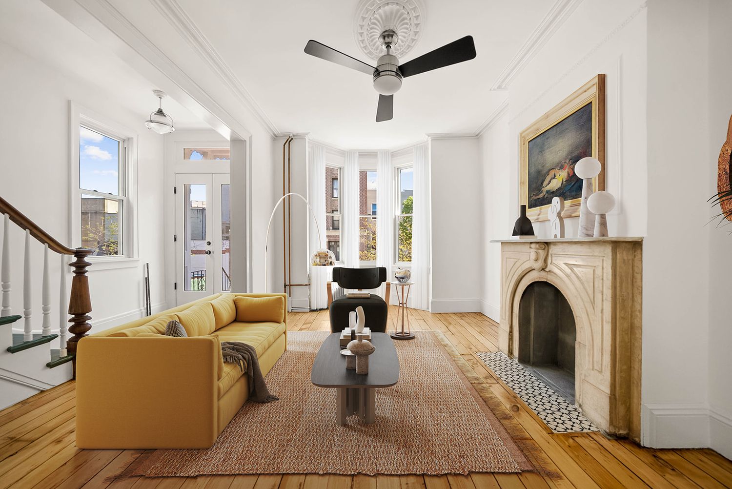 Bright Brooklyn brownstone living room with hardwood floors, marble fireplace, yellow sofa, and bay windows.