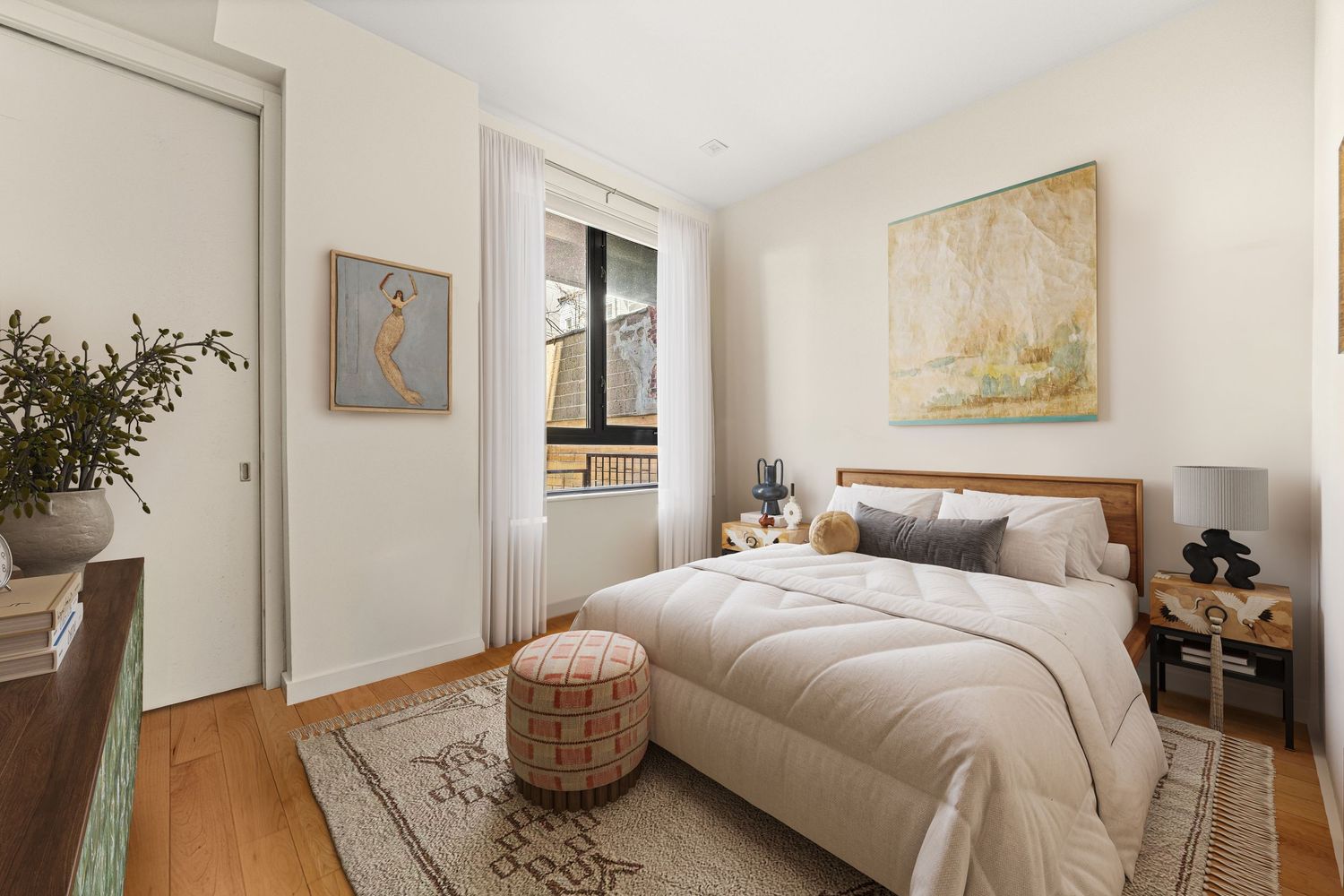 Cozy bedroom with hardwood floors, neutral tones, wood-framed bed, patterned rug, and abstract wall art near a window.