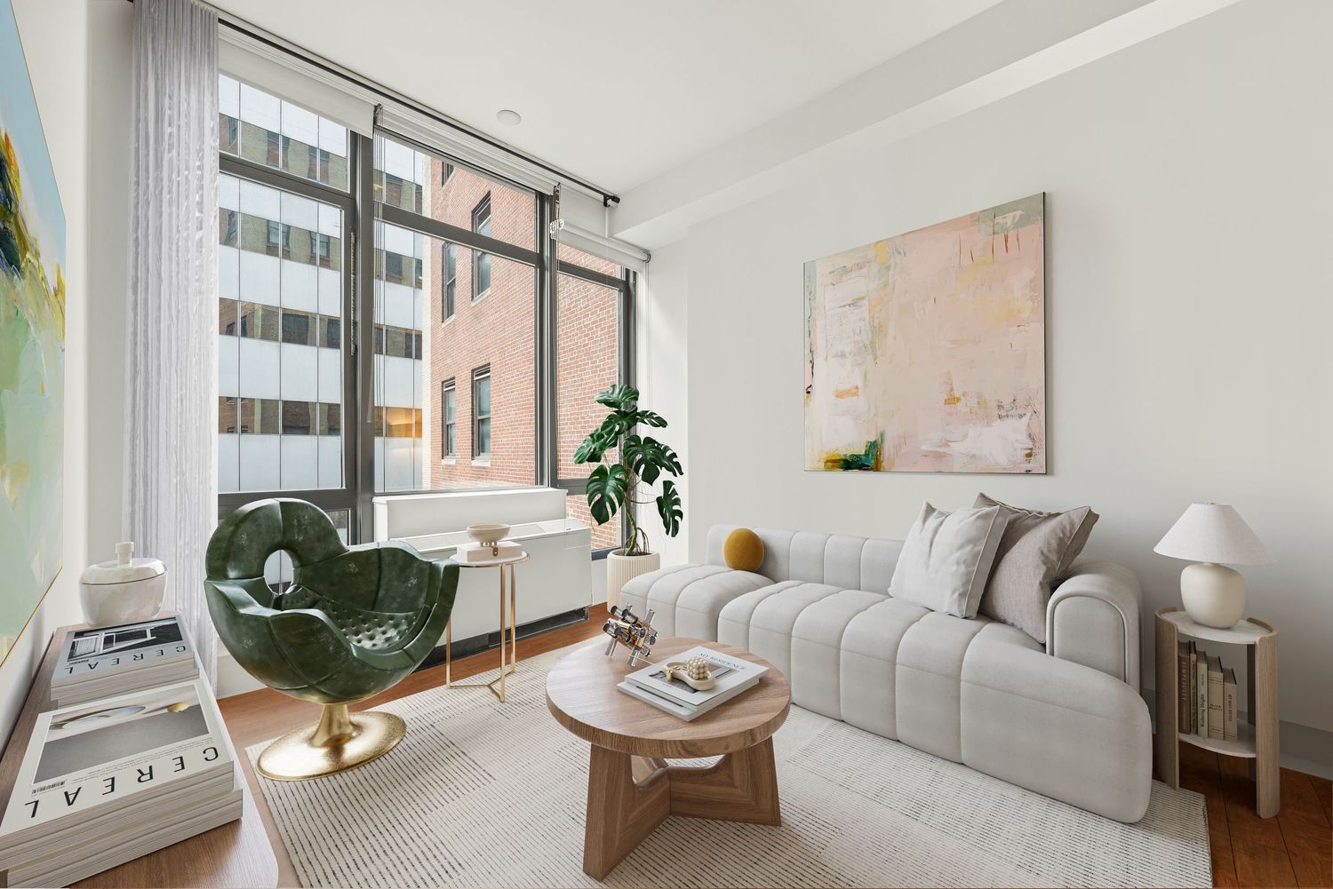 Modern living room with gray sofa, round wood coffee table, green accent chair, and large windows overlooking city buildings.