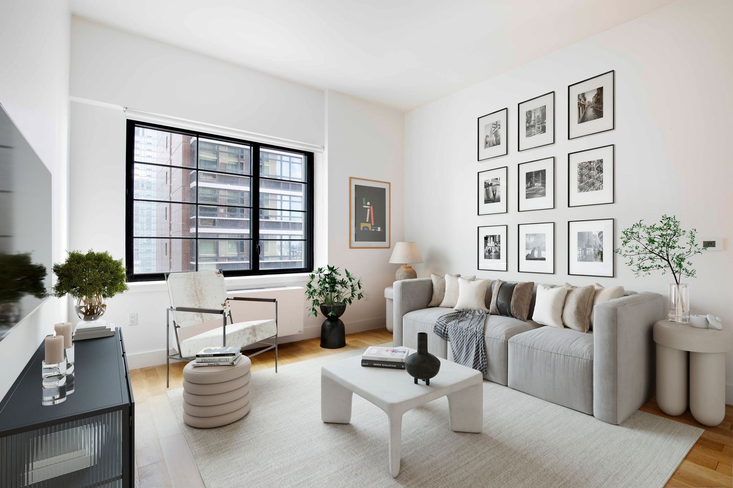 Modern living room with gray sofa, gallery wall, large windows, and minimalist white coffee table on a neutral area rug.