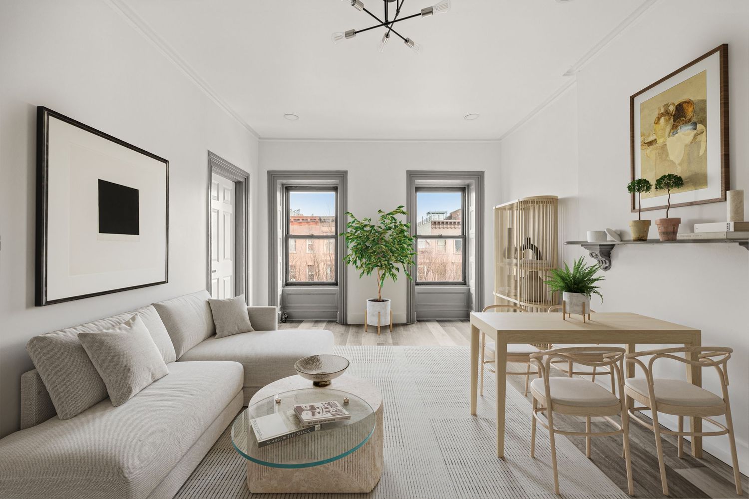 Bright modern living room with gray sectional sofa, glass coffee table, dining set, and large windows in a white apartment.