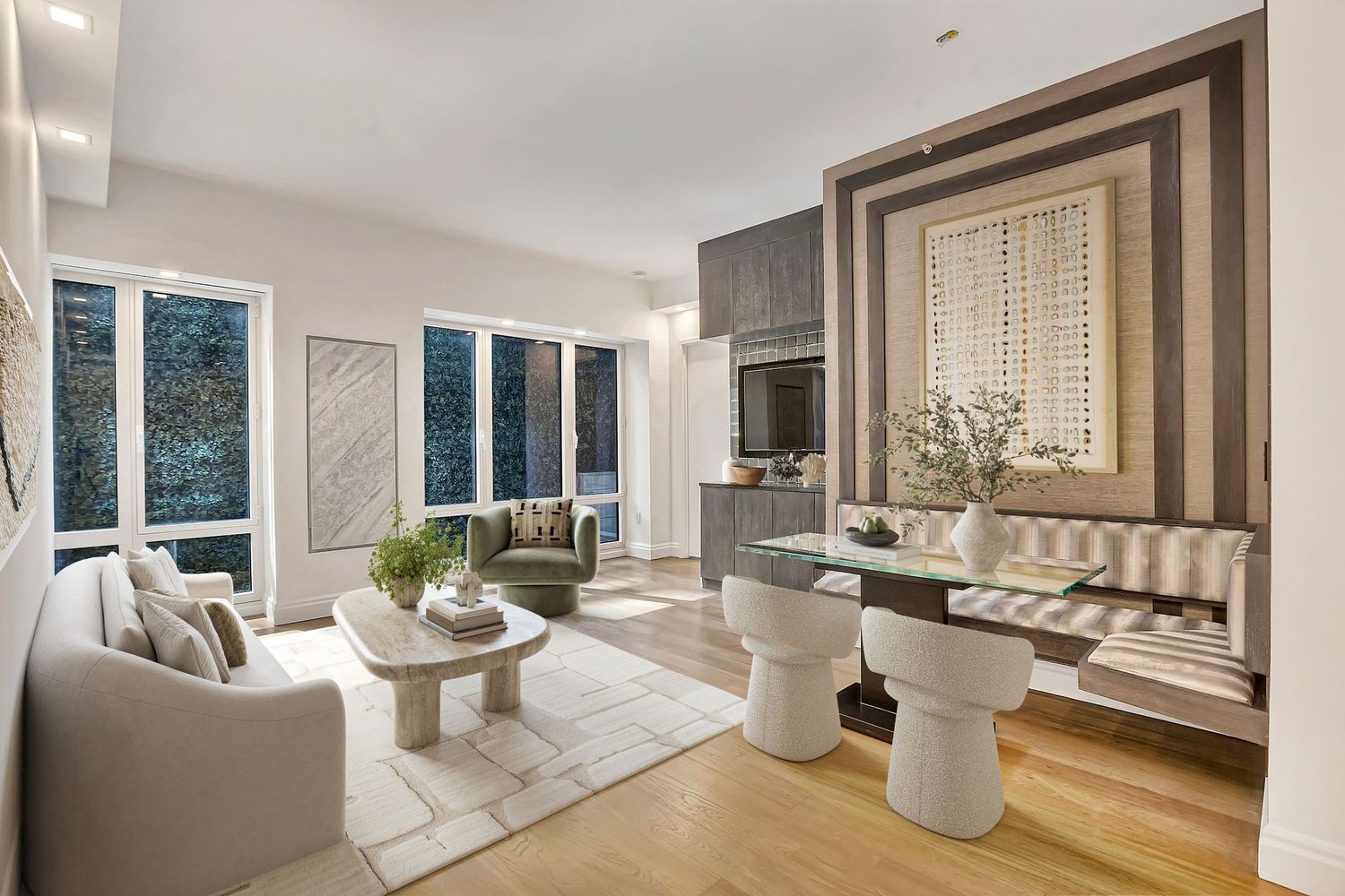 Modern living and dining room with light wood floors, neutral sofa, round coffee table, and elegant built-in banquette seating.