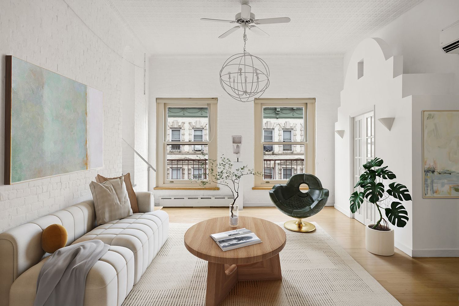 Bright modern living room with white sofa, wood coffee table, ceiling fan, chandelier, and large windows with city views.