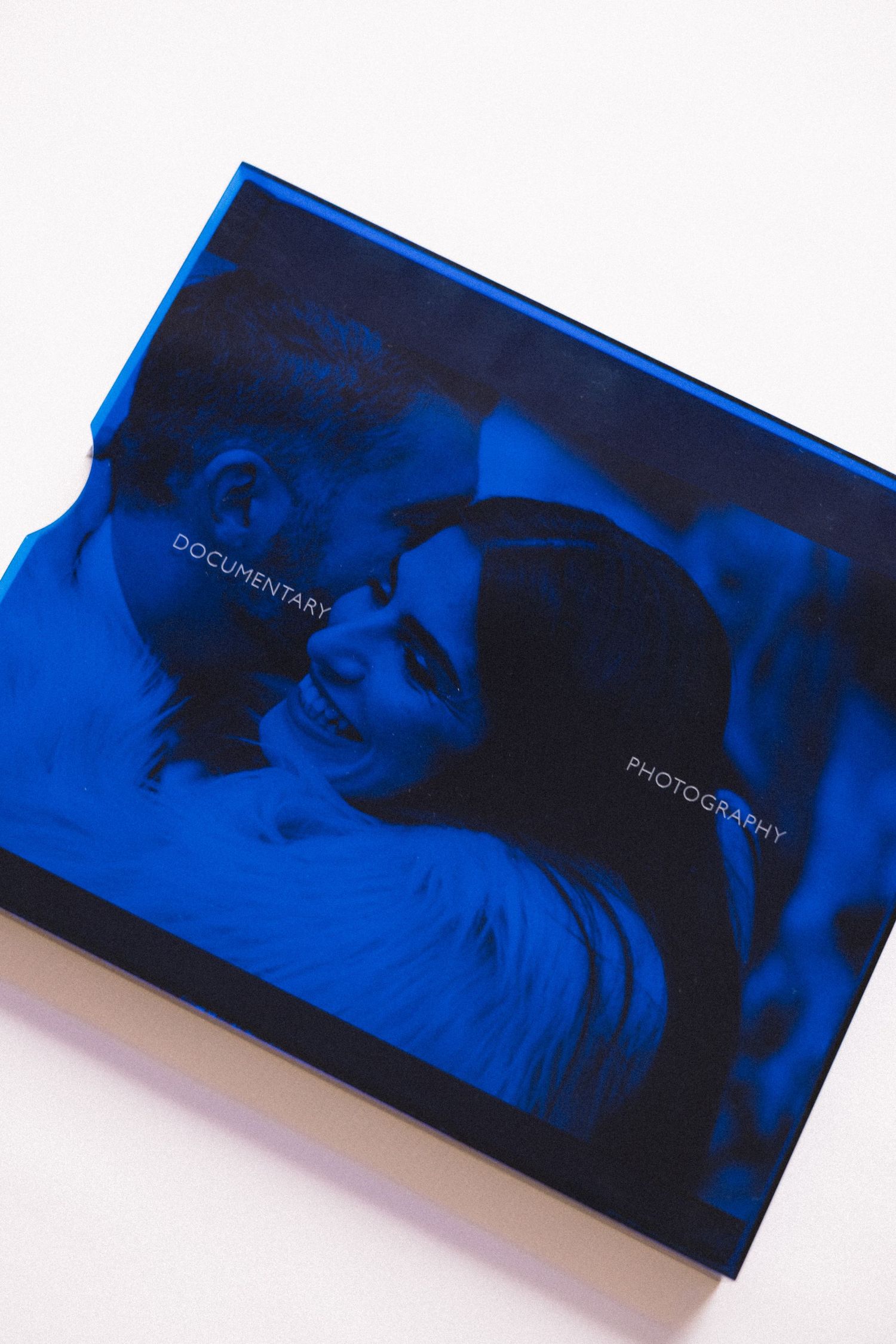 A square photo book with a blue transparent cover shows a couple embracing, labeled Documentary Photography.
