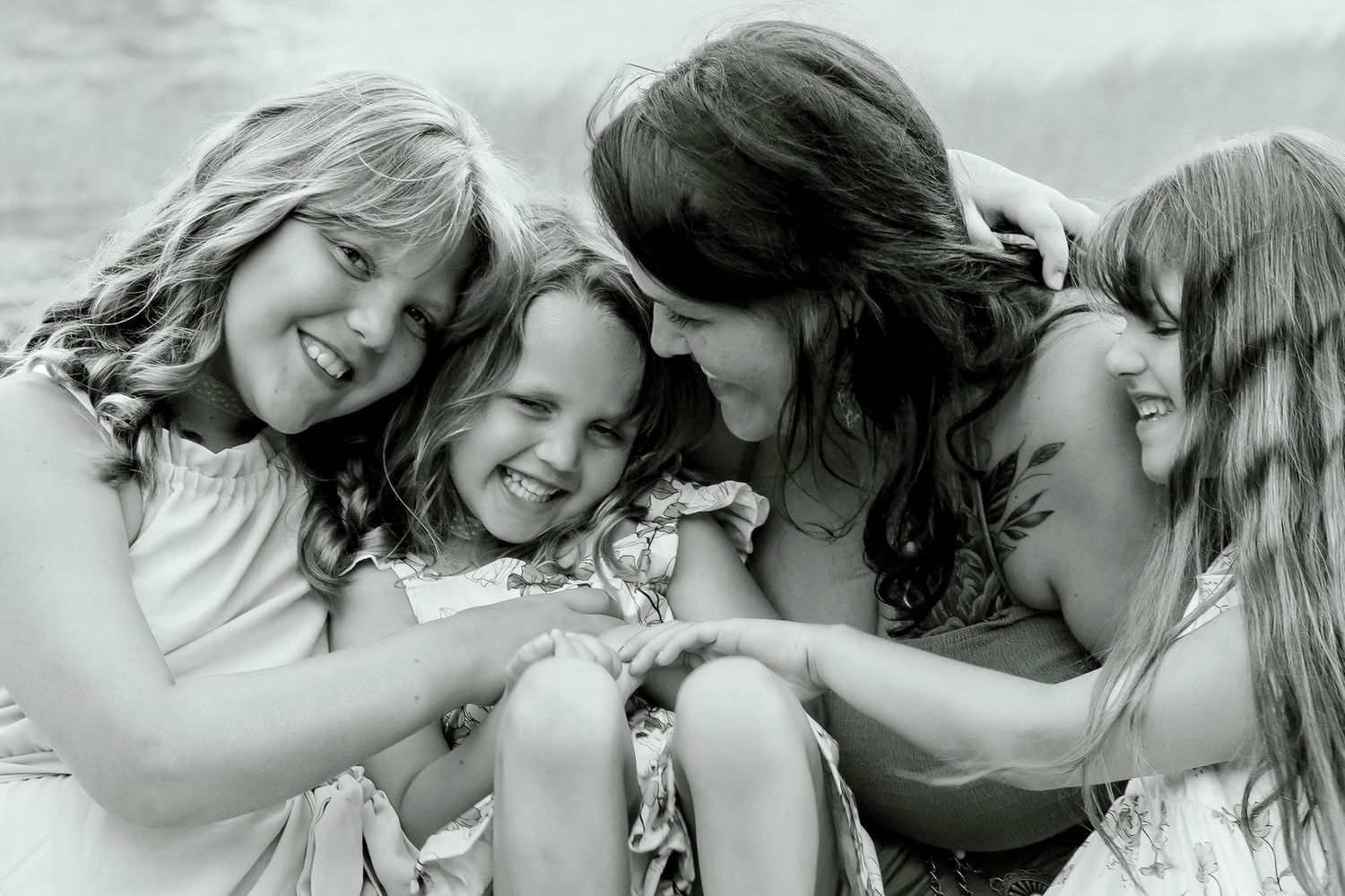 Black and white photo of a mother laughing joyfully with her three daughters.