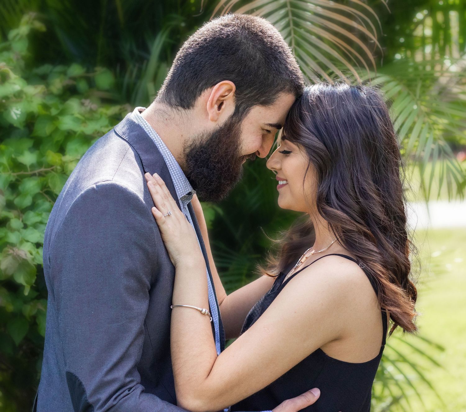 Romantic couple sharing an intimate moment outdoors, surrounded by lush green tropical foliage.