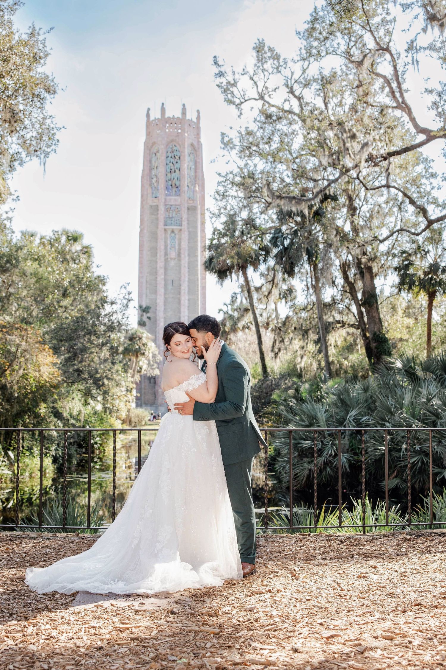 Bride and groom embracing in front of historic tower at Bok Tower Gardens.
