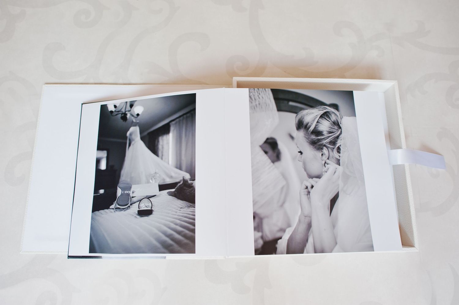 Open wedding photo album displaying black and white images of bridal gown and bride preparation.