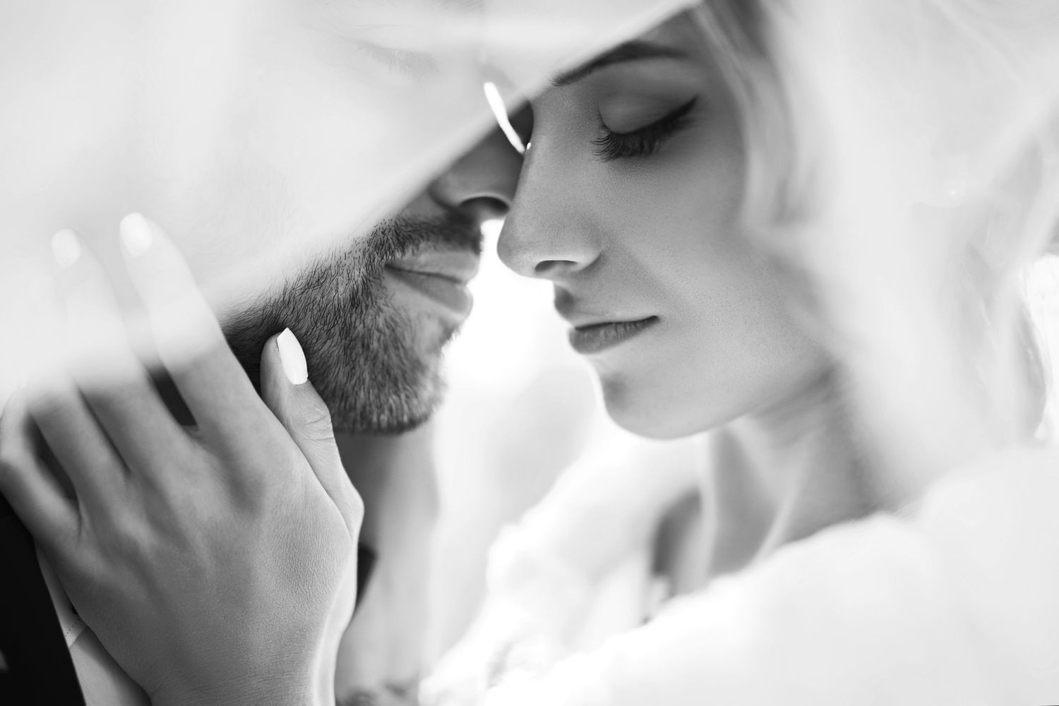 A romantic black and white close-up of a bride and groom touching foreheads on their wedding day.