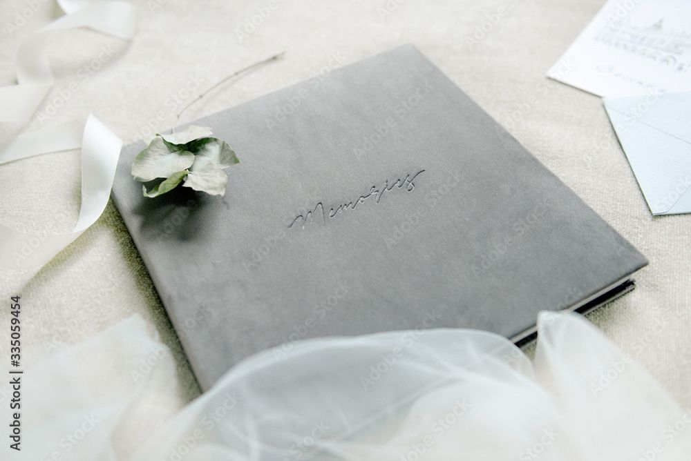 Gray velvet wedding guest book with floral embossing surrounded by white tulle and ribbon.