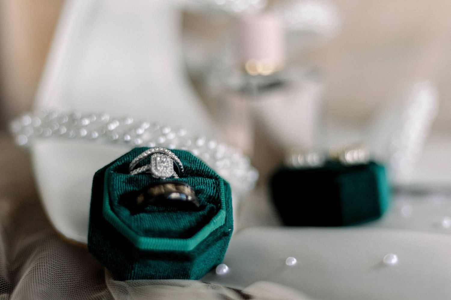 Diamond engagement ring and wedding band displayed in elegant green velvet ring box.