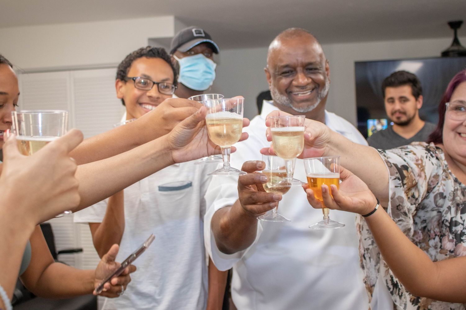 Diverse group of people toasting with glasses of wine and spirits at an indoor celebration party.