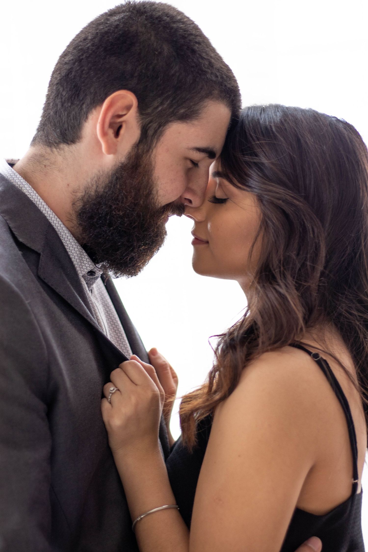 Romantic couple sharing an intimate moment, foreheads touching, eyes closed, in elegant formal attire.
