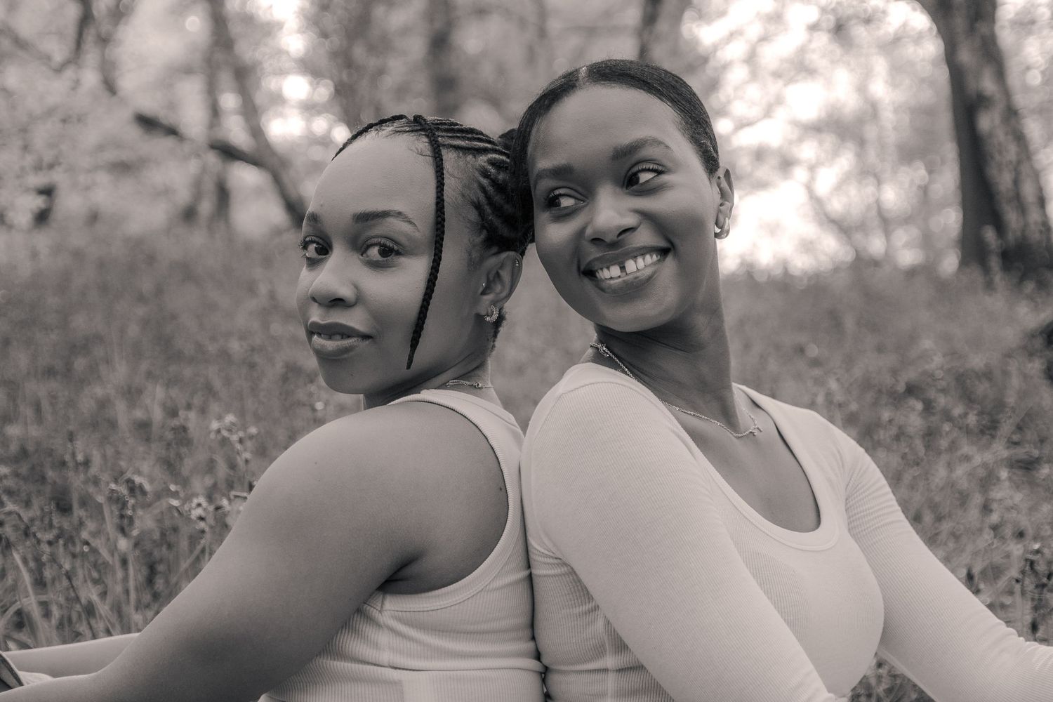 Sisters sitting back to back. Black and white photography.